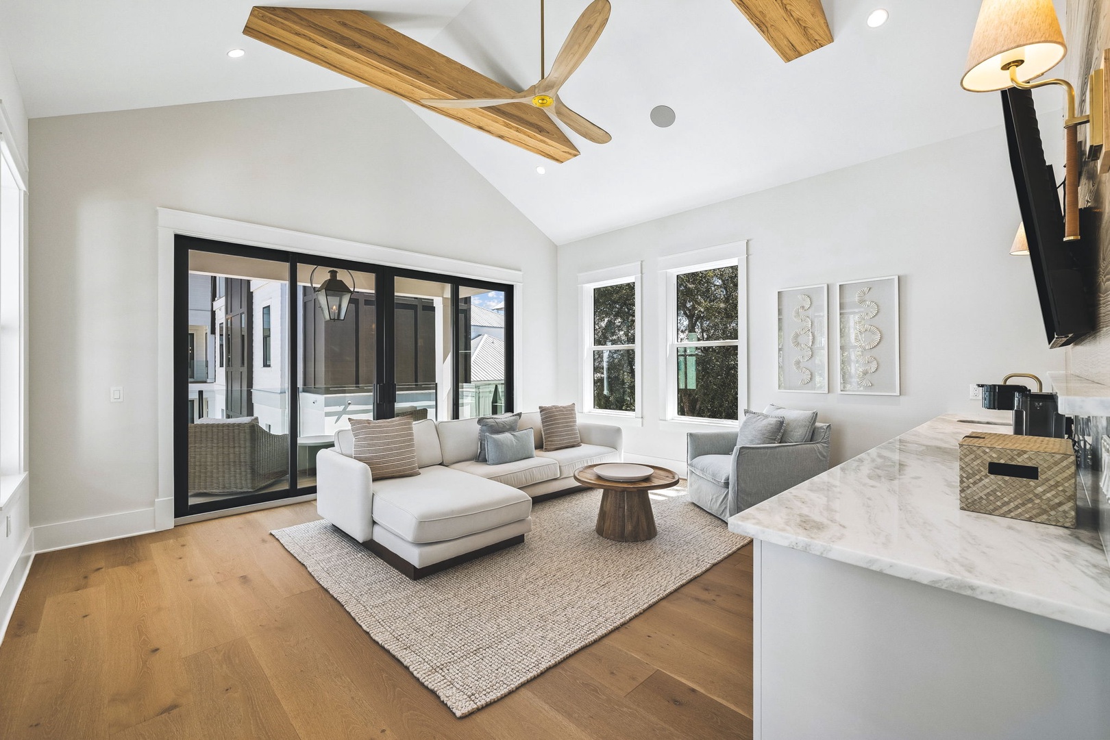 Your bright, airy living space invites relaxation with its soaring vaulted ceilings, soft natural light streaming through large windows, and comfortable seating for lounging or gathering with loved ones.