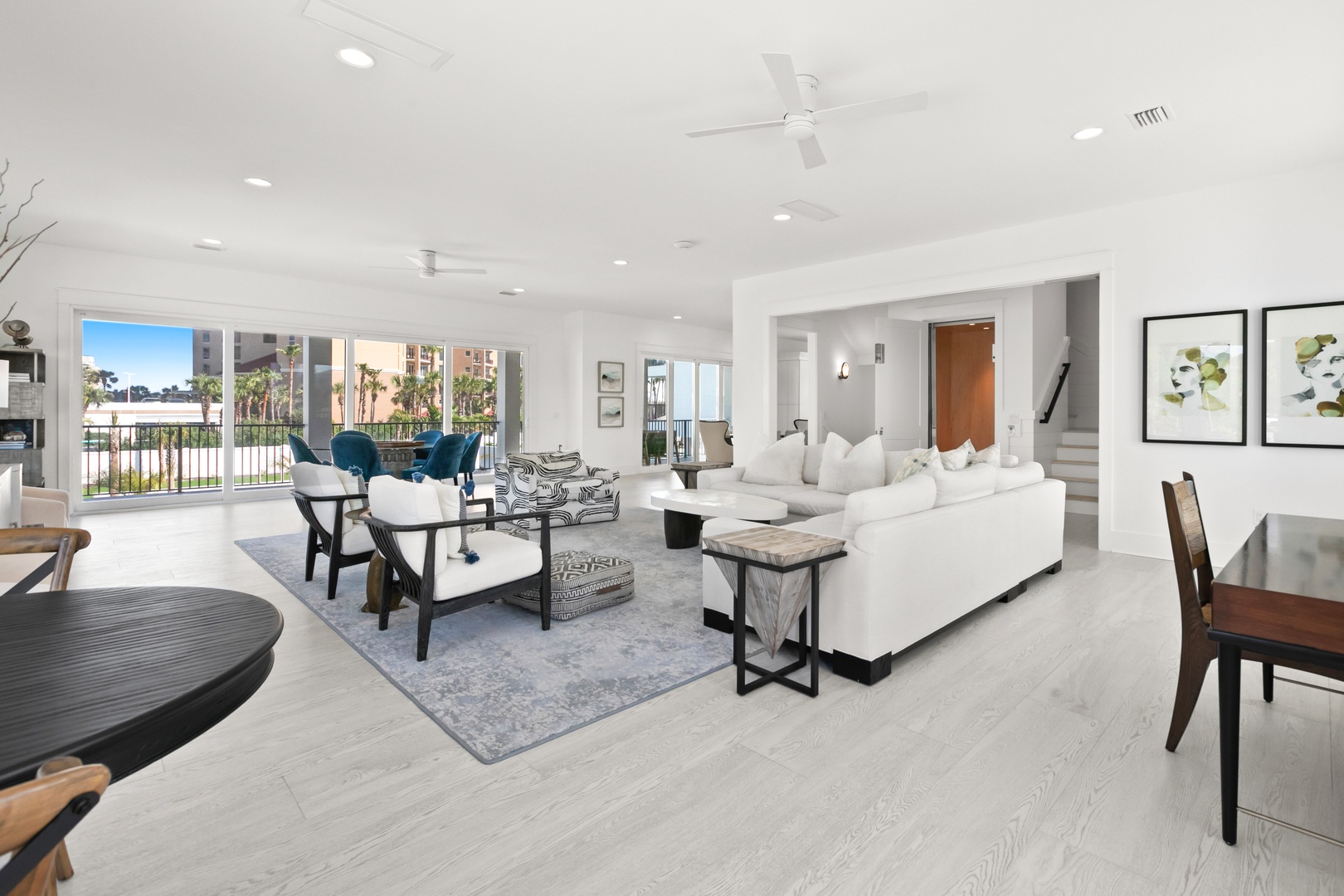 Settle into this bright, airy living room where white sofas invite you to relax while palm trees and sunshine stream through the balcony doors. The open layout flows seamlessly, giving you space to unwind.