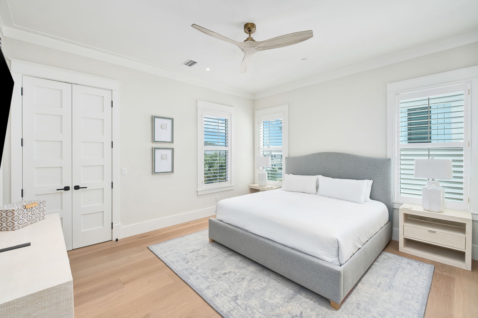 Slip into crisp white linens and let the coastal breeze from the ceiling fan drift over you in this serene bedroom—your peaceful retreat awaits.