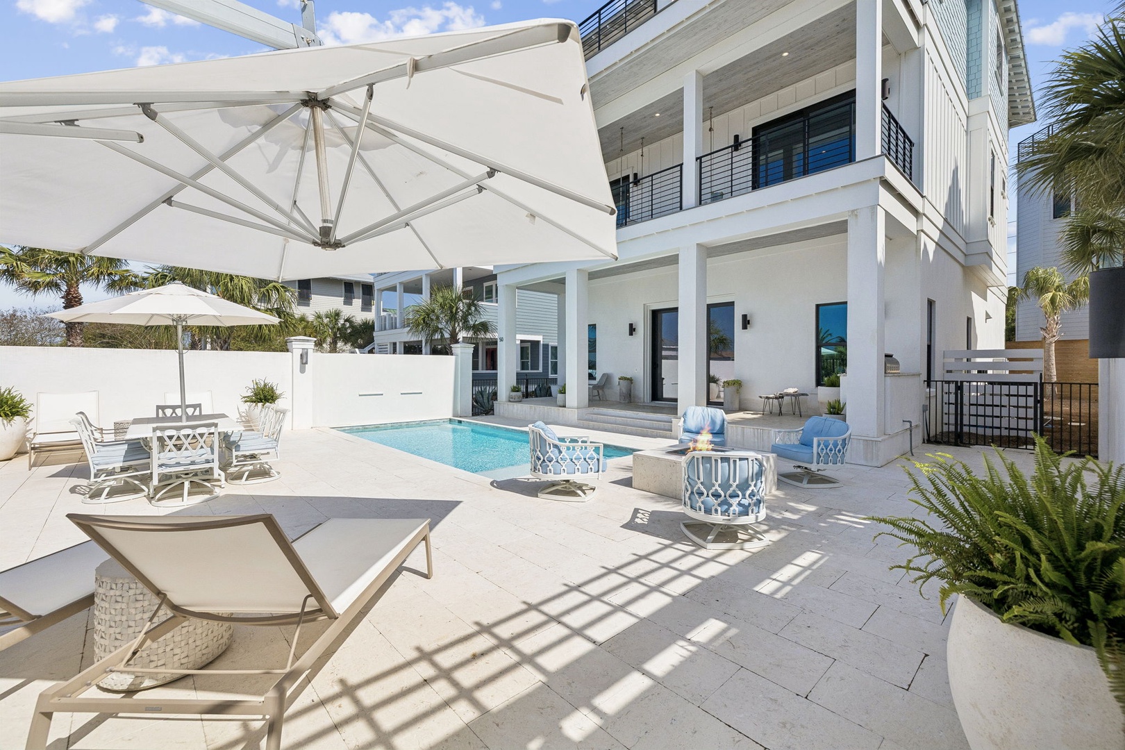 Your private outdoor oasis features a sparkling pool, comfortable lounge chairs, and shaded dining beneath elegant umbrellas—perfect for sunny days of relaxation.