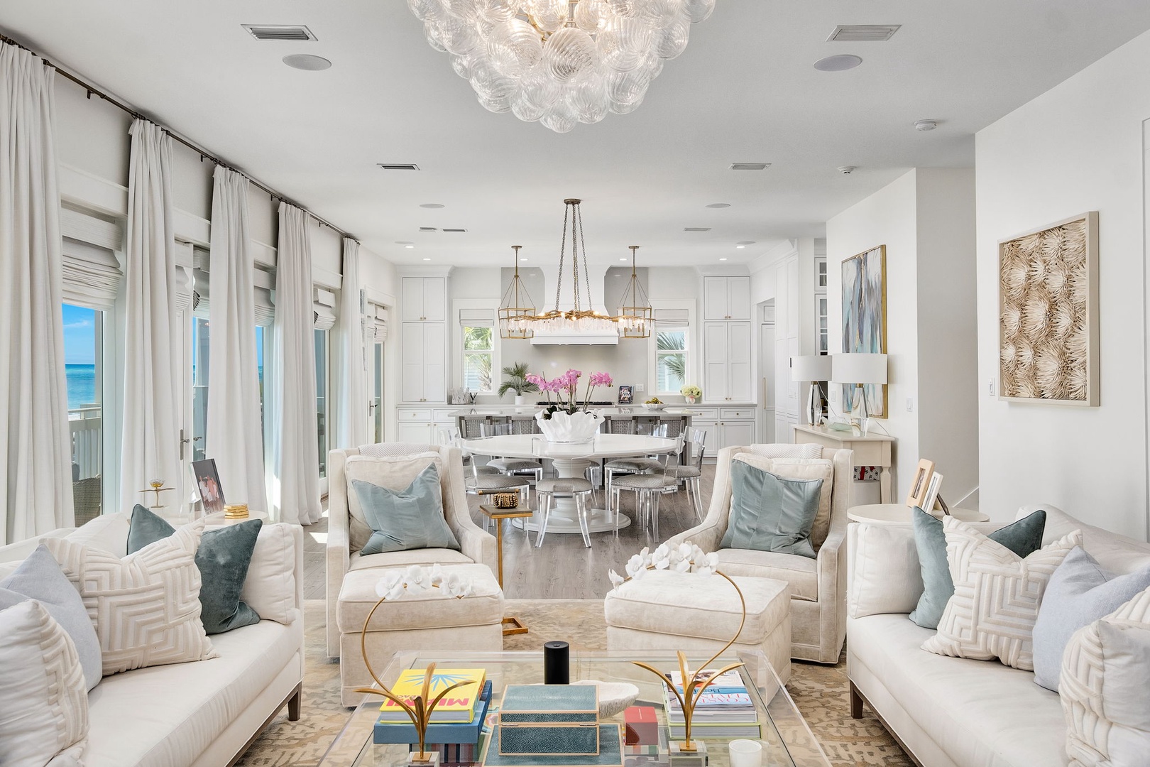 Step into this bright, elegant living space where plush white sofas and tranquil blue accents invite you to unwind. Floor-to-ceiling windows frame stunning ocean views, filling your retreat with natural light.
