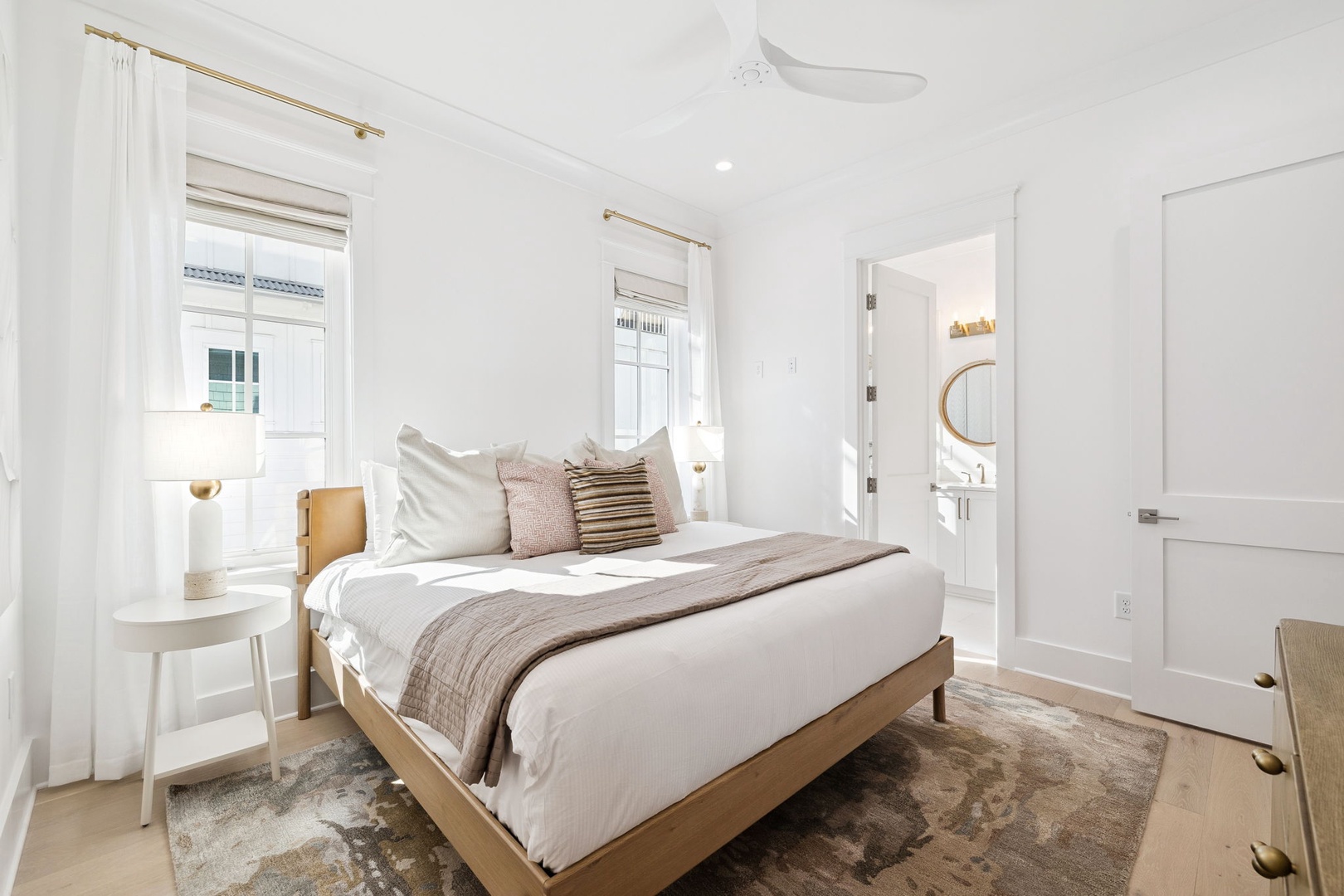 Sink into crisp white linens and warm wood accents in your serene bedroom retreat, where natural light streams through elegant windows.