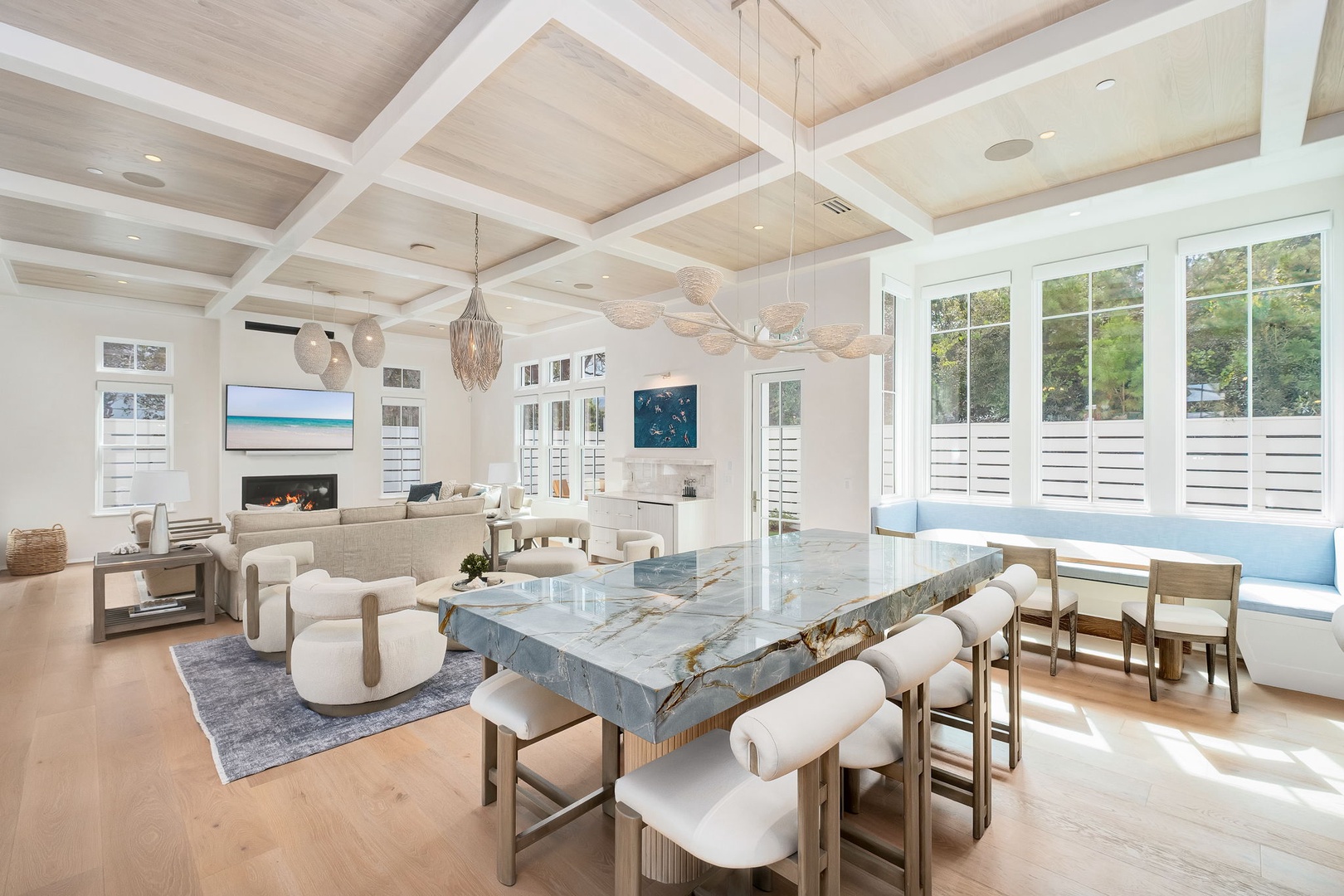 Gather around the stunning natural stone dining table, surrounded by soft light and elegant coastal design. With cozy seating areas and a warm fireplace nearby, every moment here feels effortlessly relaxed yet refined.