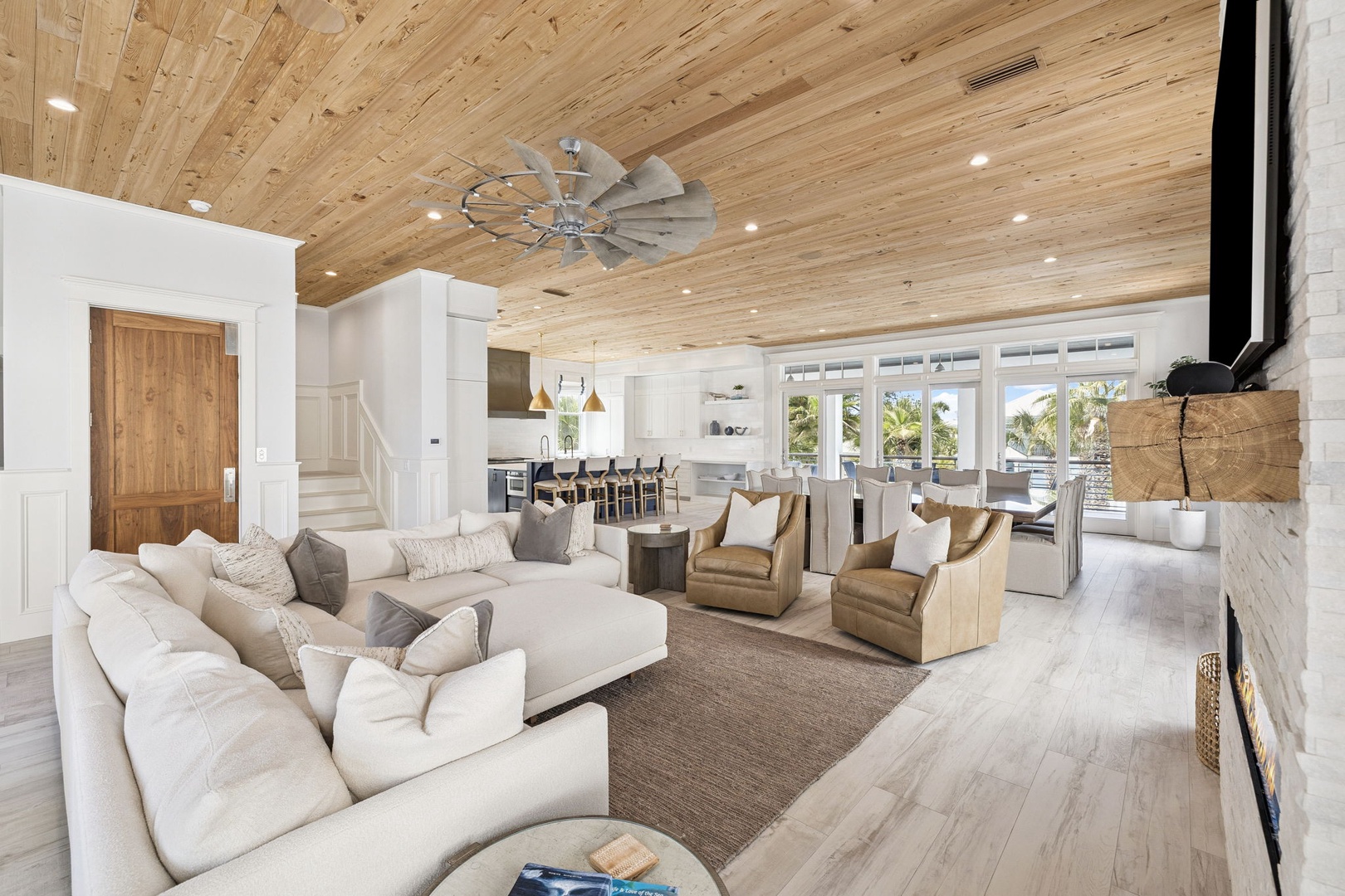Sink into plush sofas beneath soaring wood ceilings while natural light streams through expansive windows, creating your perfect gathering space.