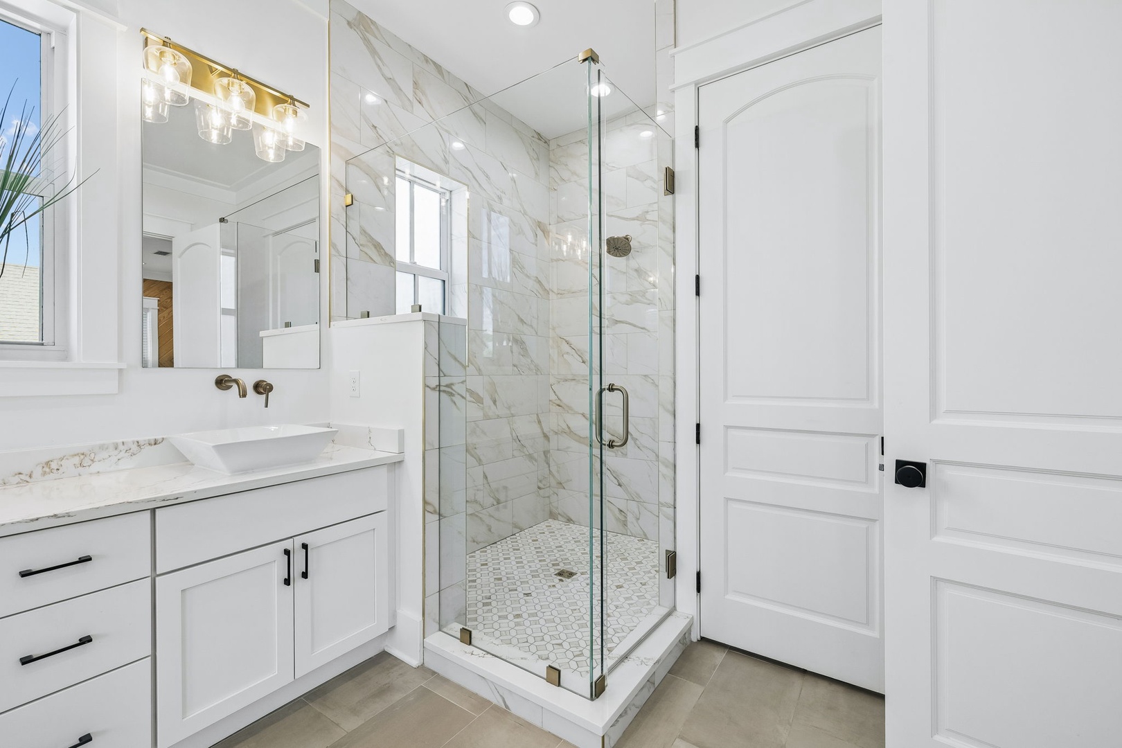 Step into your elegant private bathroom with marble-tiled shower, dual vanity, and warm lighting that makes every morning feel like a spa retreat.