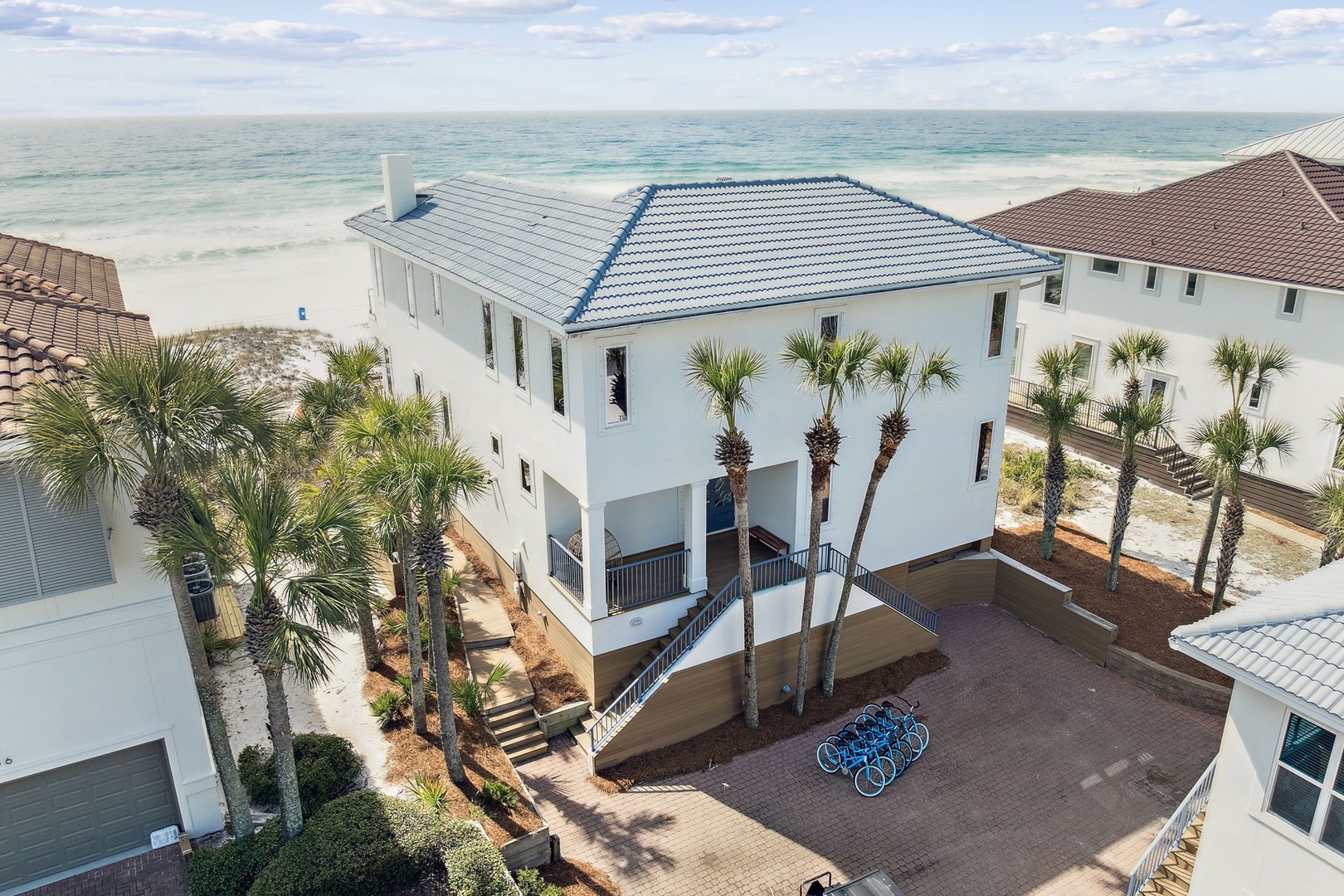 Beachfront vacation home with pristine white sand and emerald waters just steps away, surrounded by swaying palms and coastal charm.