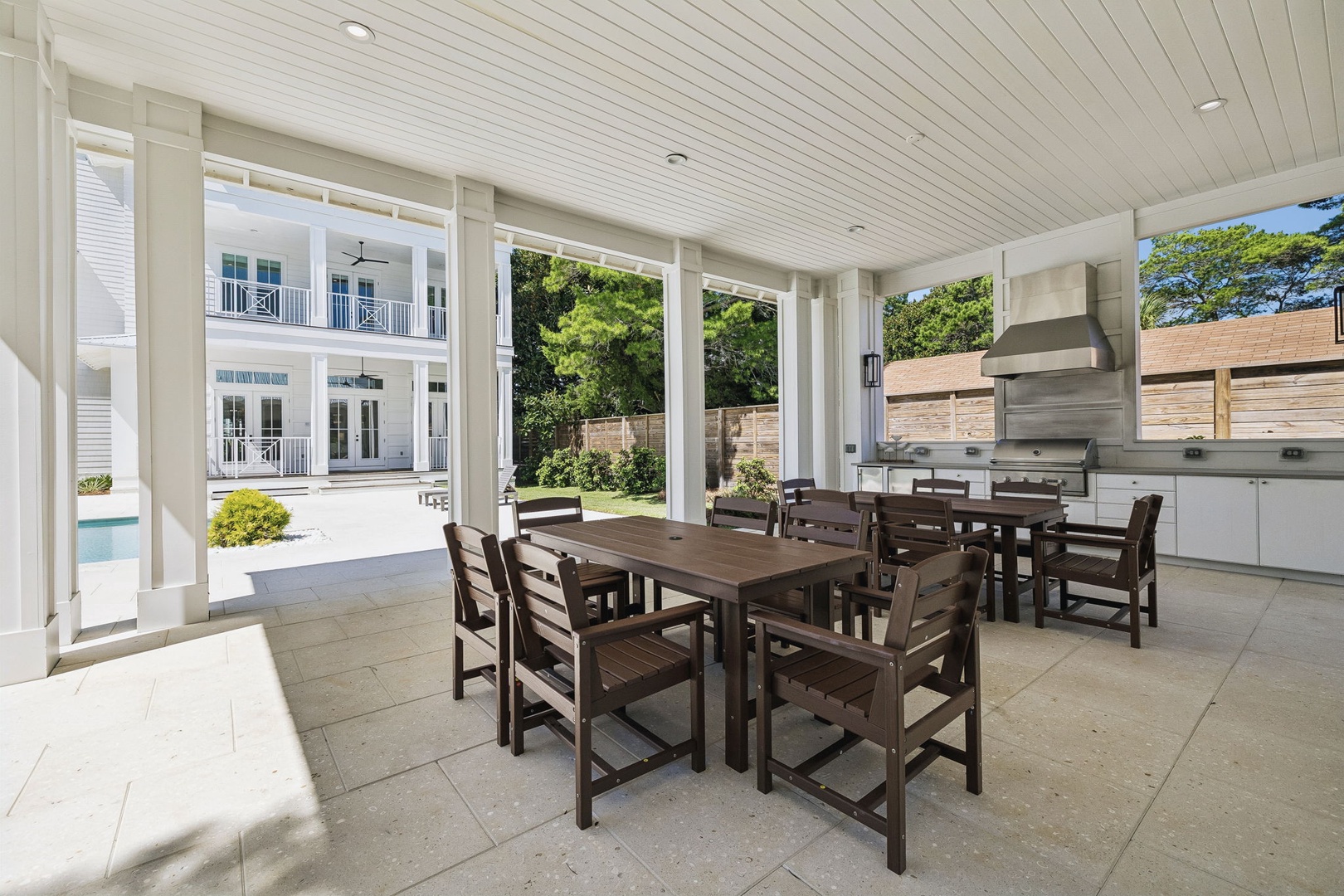 Your covered outdoor dining and kitchen area opens to lush greenery, perfect for gathering with loved ones over grilled meals and enjoying the fresh air in style.
