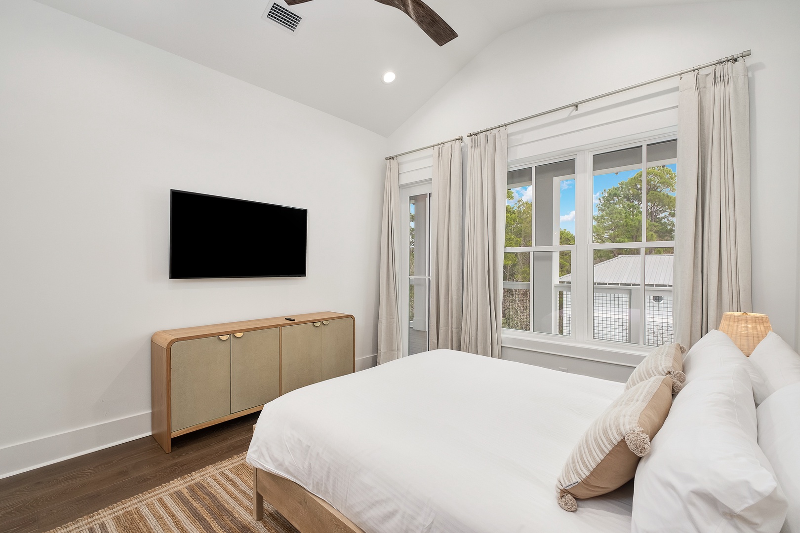 Wake up in this serene bedroom where crisp white linens meet natural light streaming through your private windows.