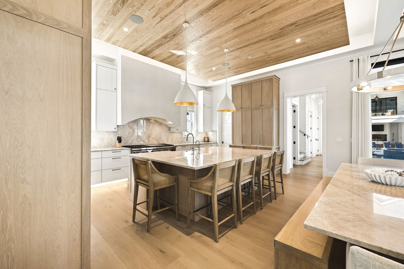 Gather around the large island in this bright, open kitchen featuring stunning wood-grain ceilings, pendant lighting, and space to cook and share meals together.