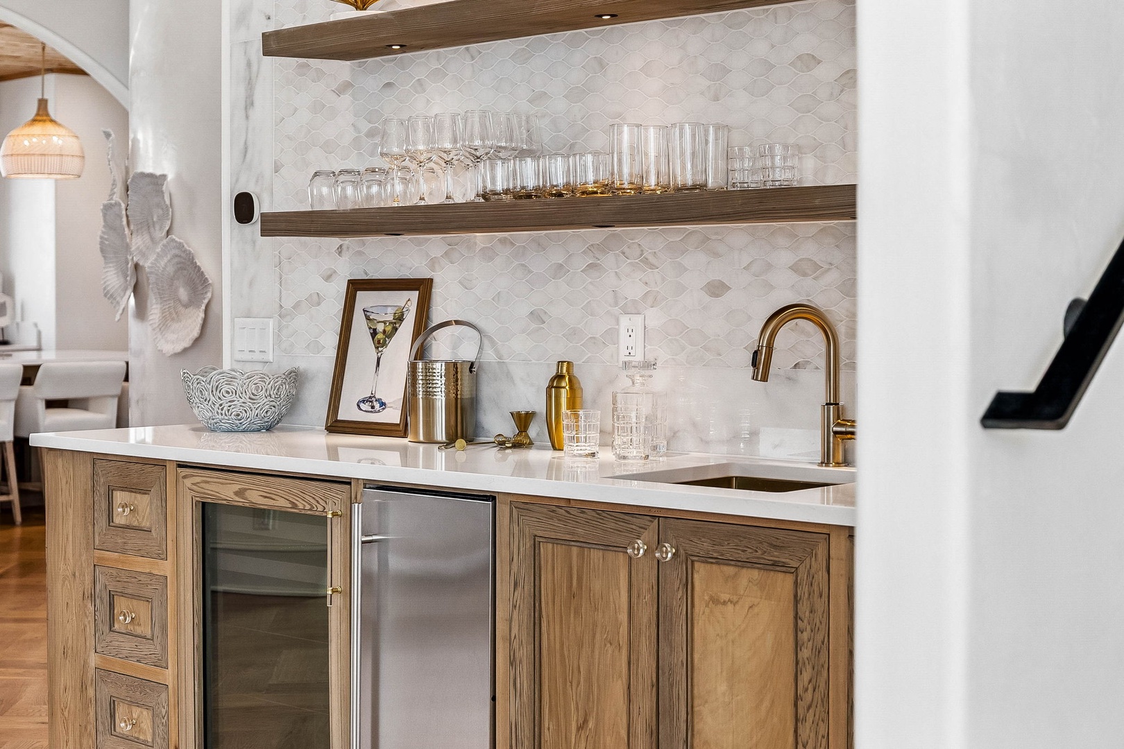 Your private wet bar awaits, featuring a wine cooler, mini-fridge, gleaming brass fixtures, and sparkling glassware—perfect for crafting your favorite cocktails and unwinding in style.