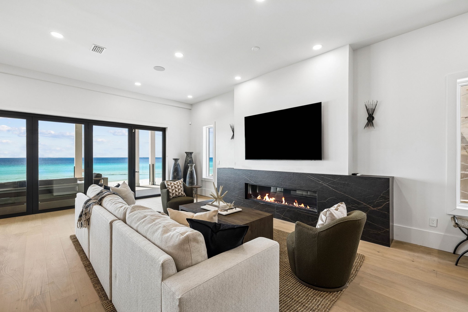 Sink into plush seating and watch the waves dance across turquoise waters through floor-to-ceiling windows. The sleek fireplace adds warmth while your oceanfront view stretches endlessly beyond.