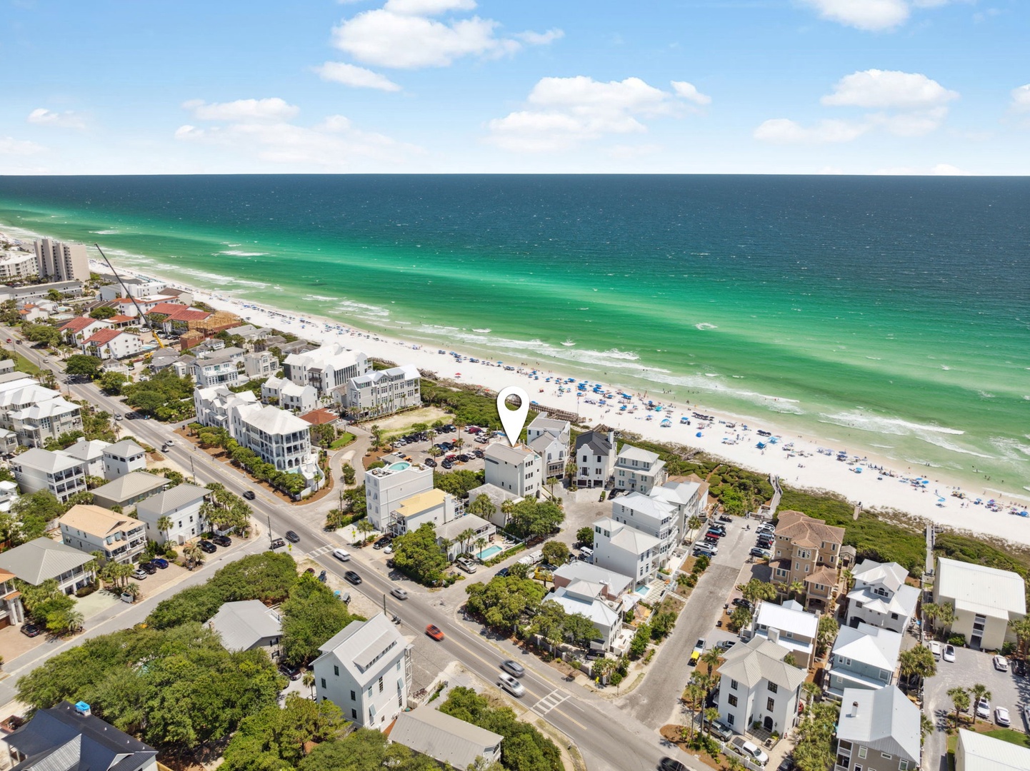 Aerial view captures the property's prime beachfront location, nestled among coastal homes with pristine white sand and emerald waters just steps away.