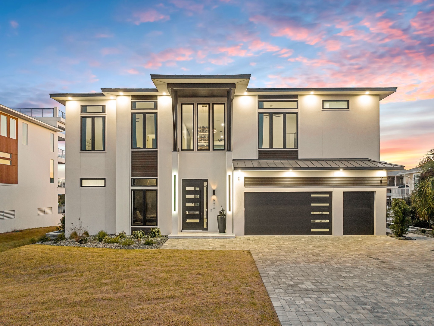 Modern luxury vacation home featuring contemporary architecture and elegant design against a stunning sunset backdrop.