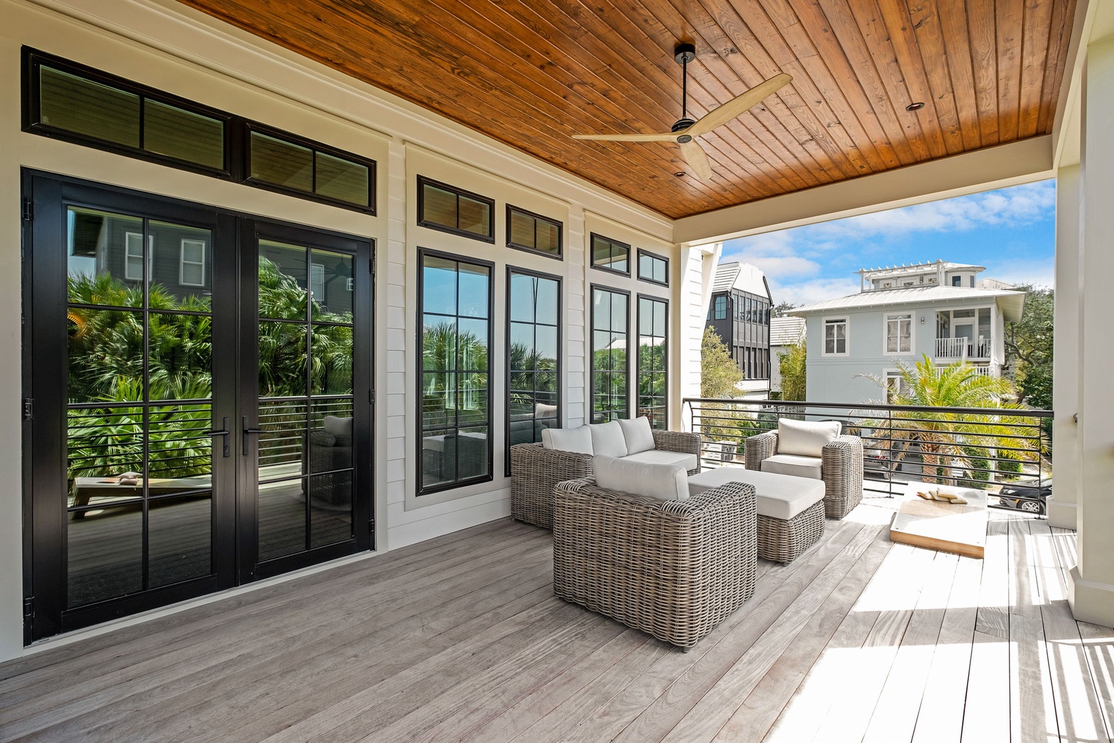 Your private balcony beckons with comfortable wicker seating under a warm wood ceiling, perfect for morning coffee or evening relaxation.