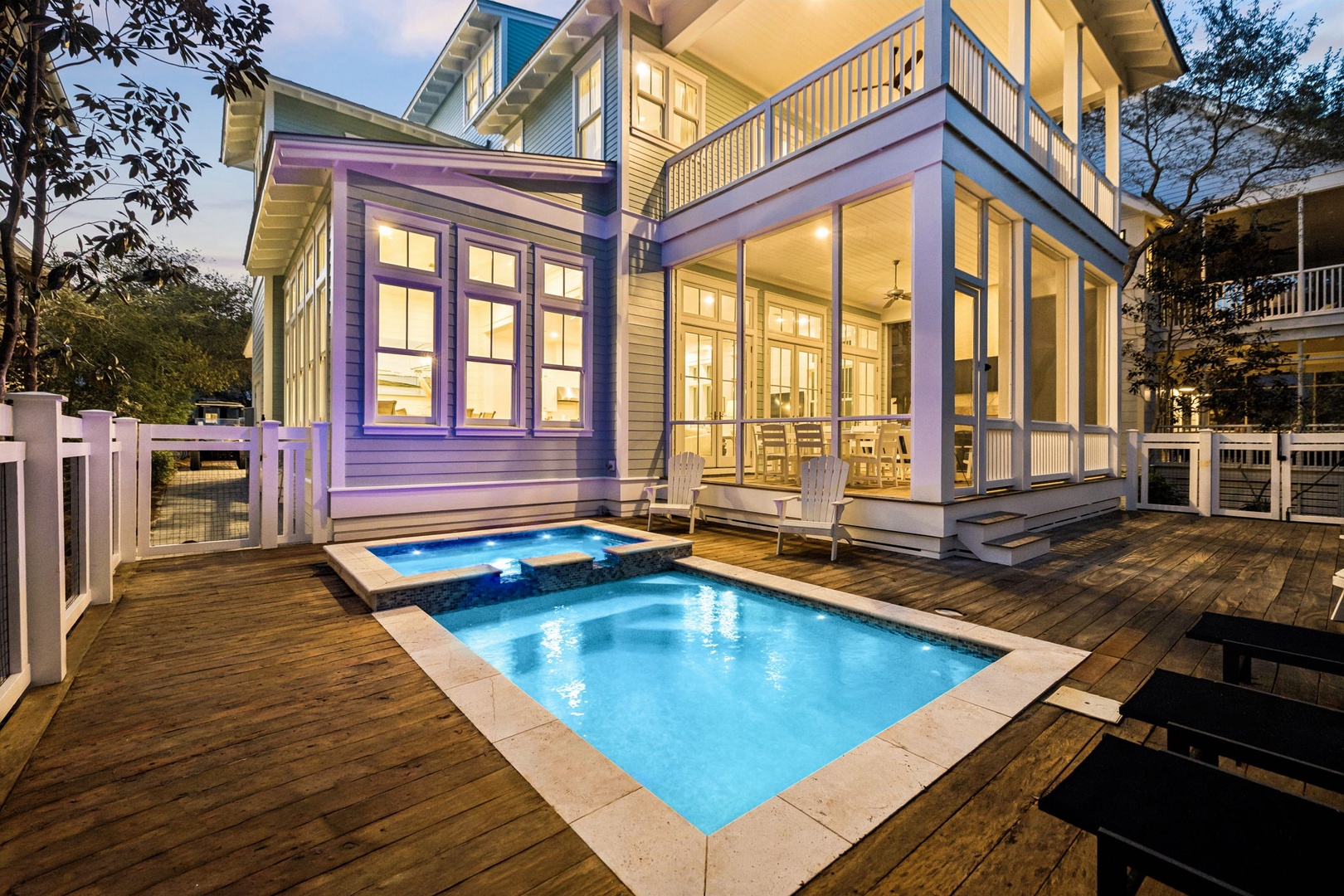 Charming coastal home featuring a private swimming pool and hot tub on an expansive wooden deck, surrounded by mature trees in a peaceful residential setting.