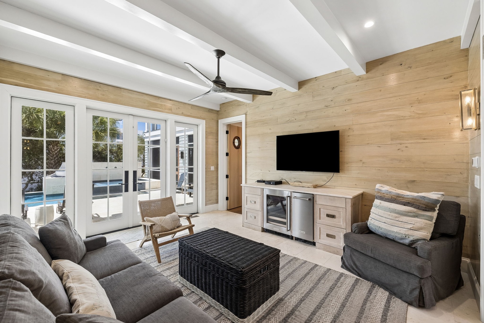 Your coastal retreat awaits, where light wood tones and modern comfort meet. Relax in this open living space with pool views through bright glass doors—perfect for lazy afternoons.