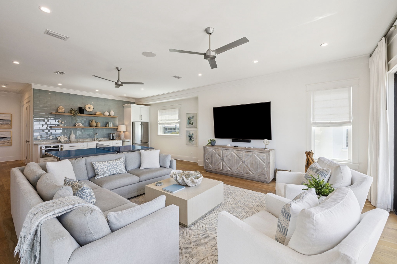 Sink into plush sofas in your bright, airy living space where coastal blues meet modern comfort beneath soaring ceilings.