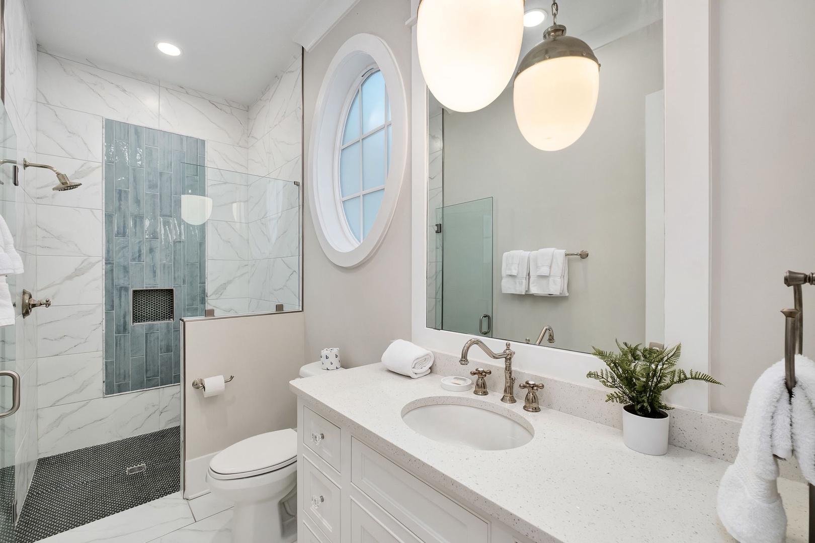 Step into your elegant marble bathroom where designer pendant lights illuminate beautiful tilework and luxury awaits in every detail.
