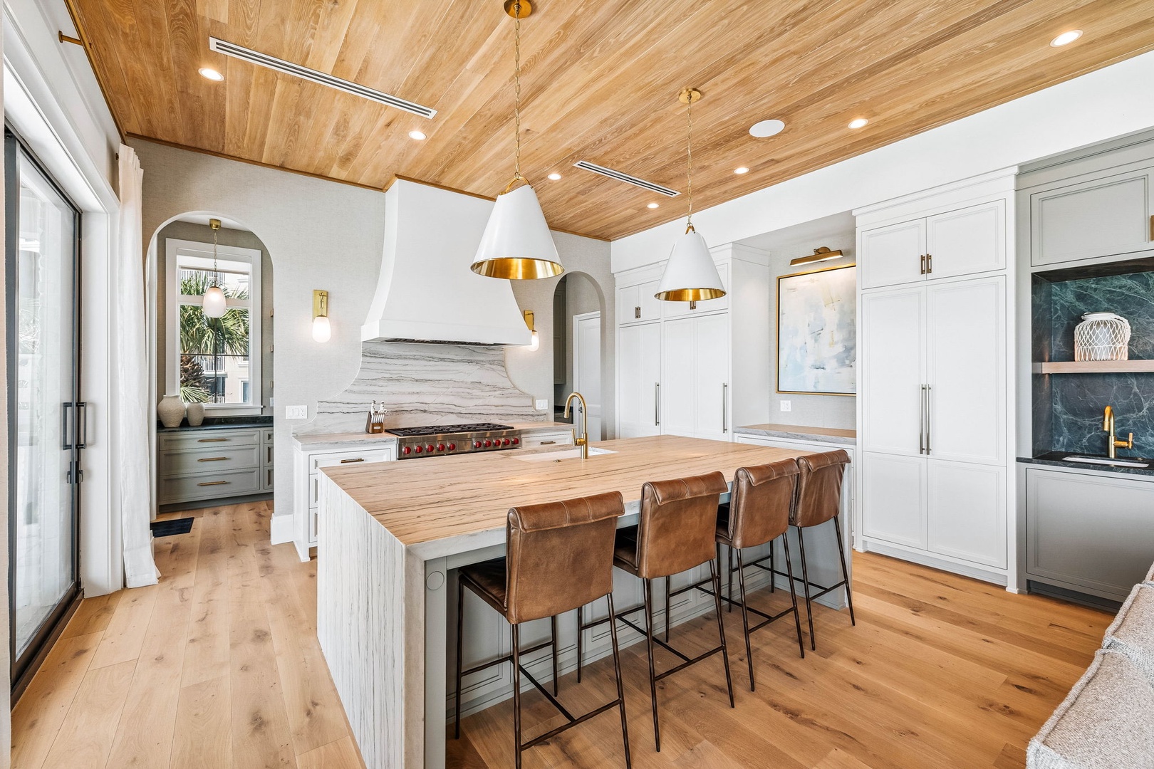 Picture yourself preparing meals in this light-filled chef's kitchen, where warm wood ceilings meet sleek marble countertops. Gather around the spacious island with friends, enjoying the elegant blend of modern design and inviting comfort.