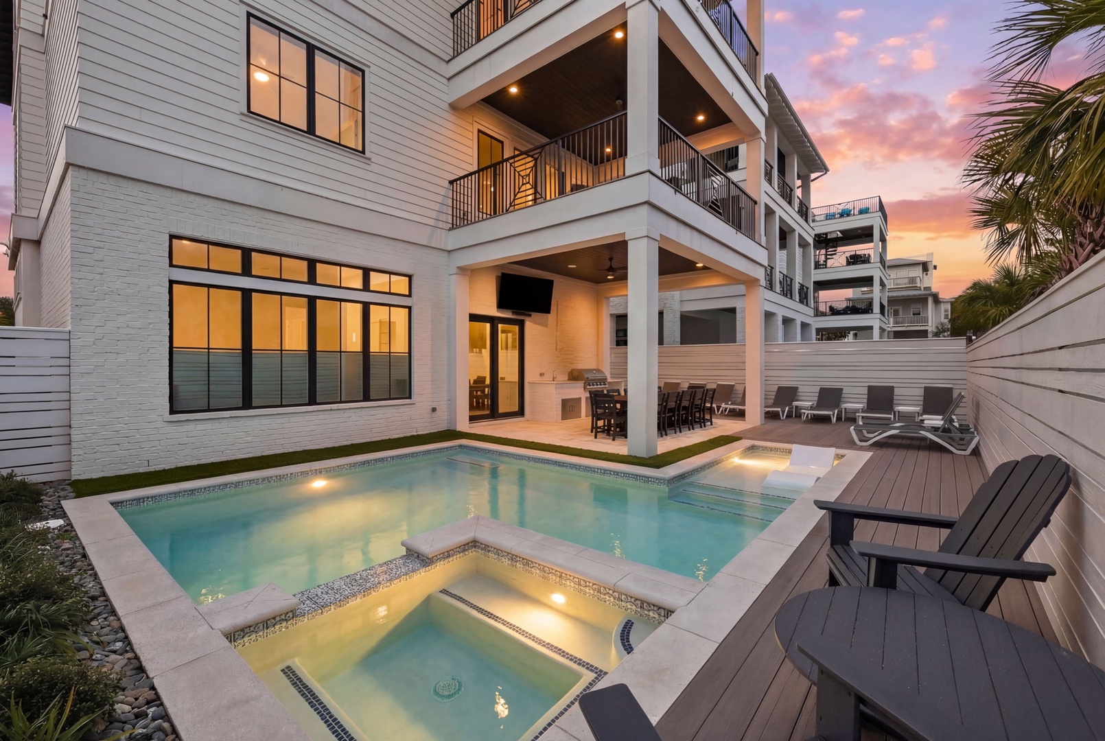 Stunning modern beach house with private pool, hot tub, and covered patio under a breathtaking sunset sky.