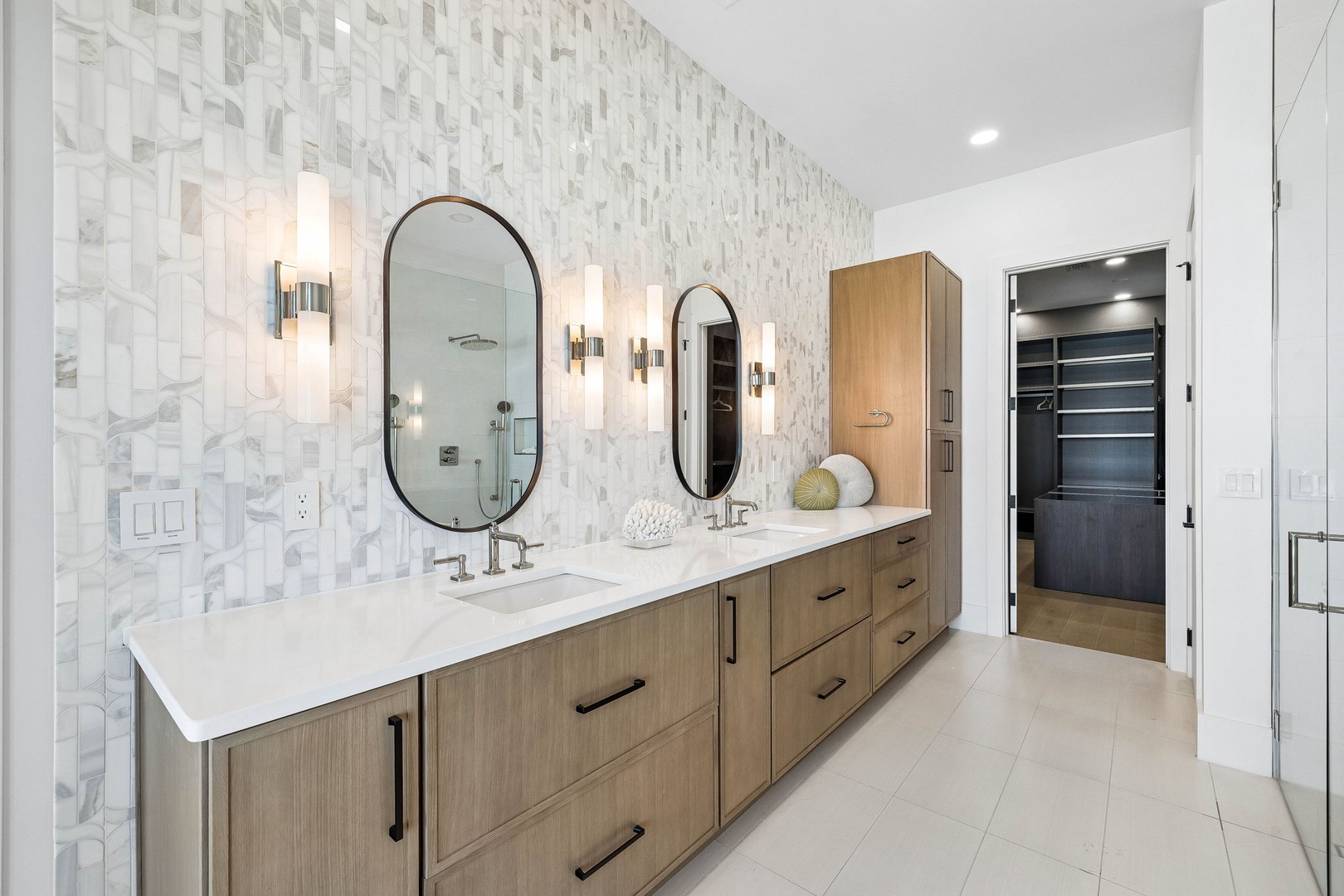 Luxurious dual-sink vanity with statement tile and sophisticated lighting creates the perfect space for your morning routine. Custom cabinetry offers plenty of storage to keep your retreat organized and serene.