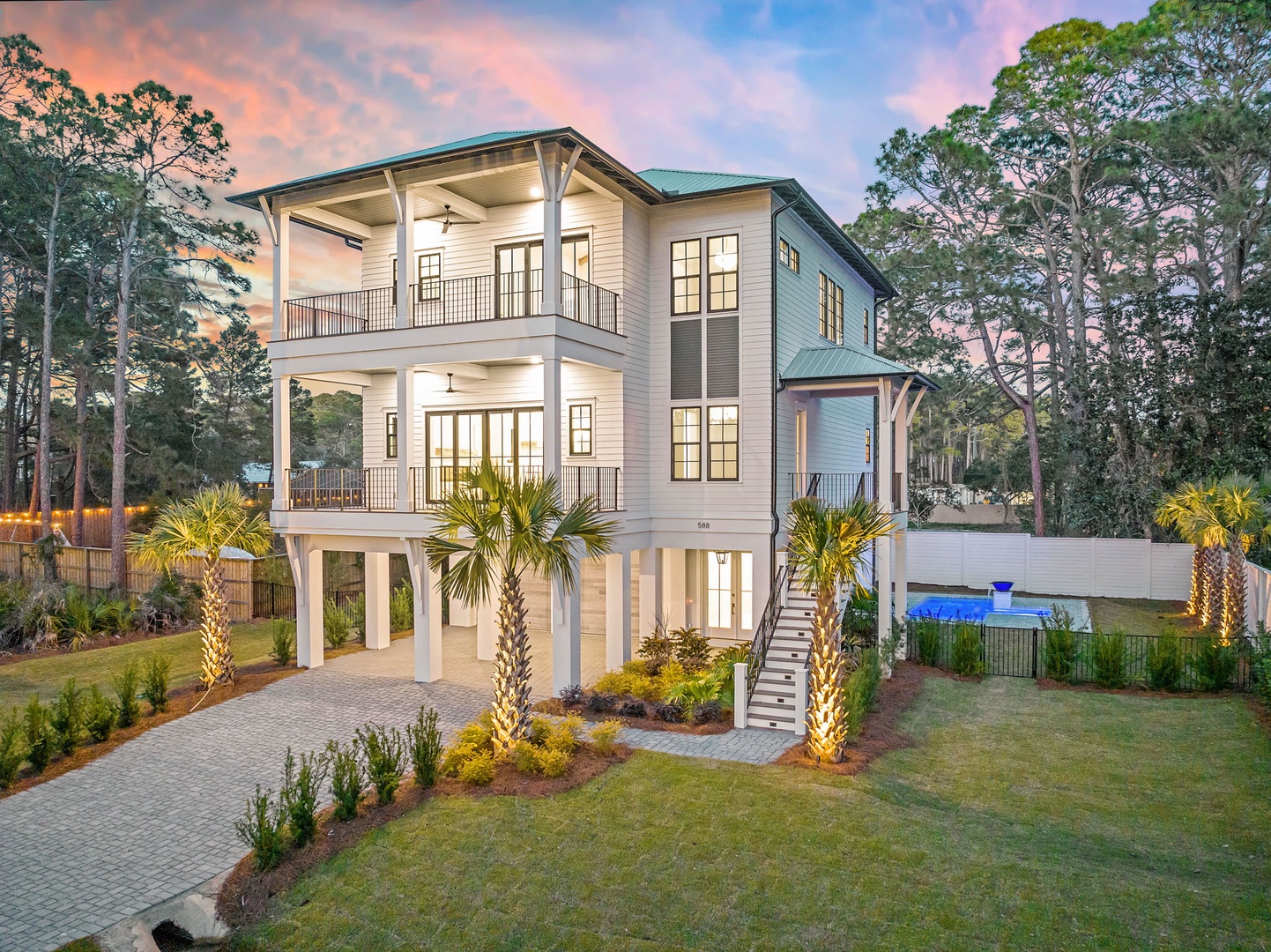 Stunning coastal property featuring a three-story design with covered balconies, tropical landscaping, and a sparkling pool nestled among mature trees.