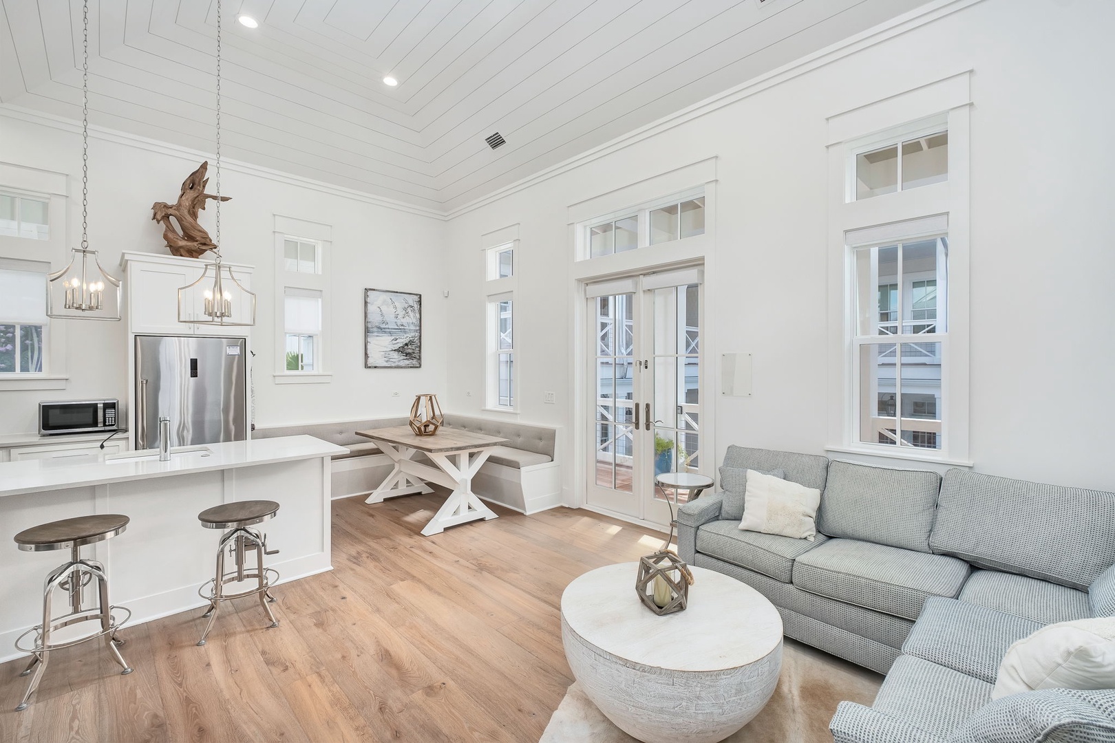 Step into an airy, light-filled open living space where vaulted ceilings and coastal accents create the perfect retreat. Relax on plush seating or gather around the rustic dining table—your home away from home awaits.