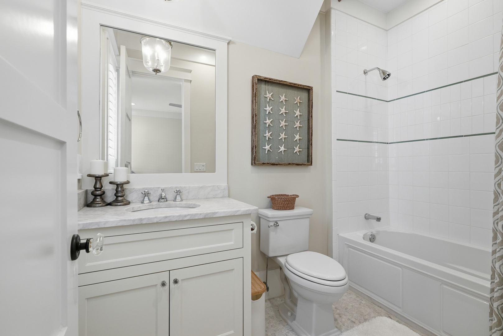 Refresh in your crisp, coastal bathroom with classic subway tiles, a soothing tub-shower combo, and charming seaside touches. The bright vanity and starfish décor create a breezy, beachy vibe.