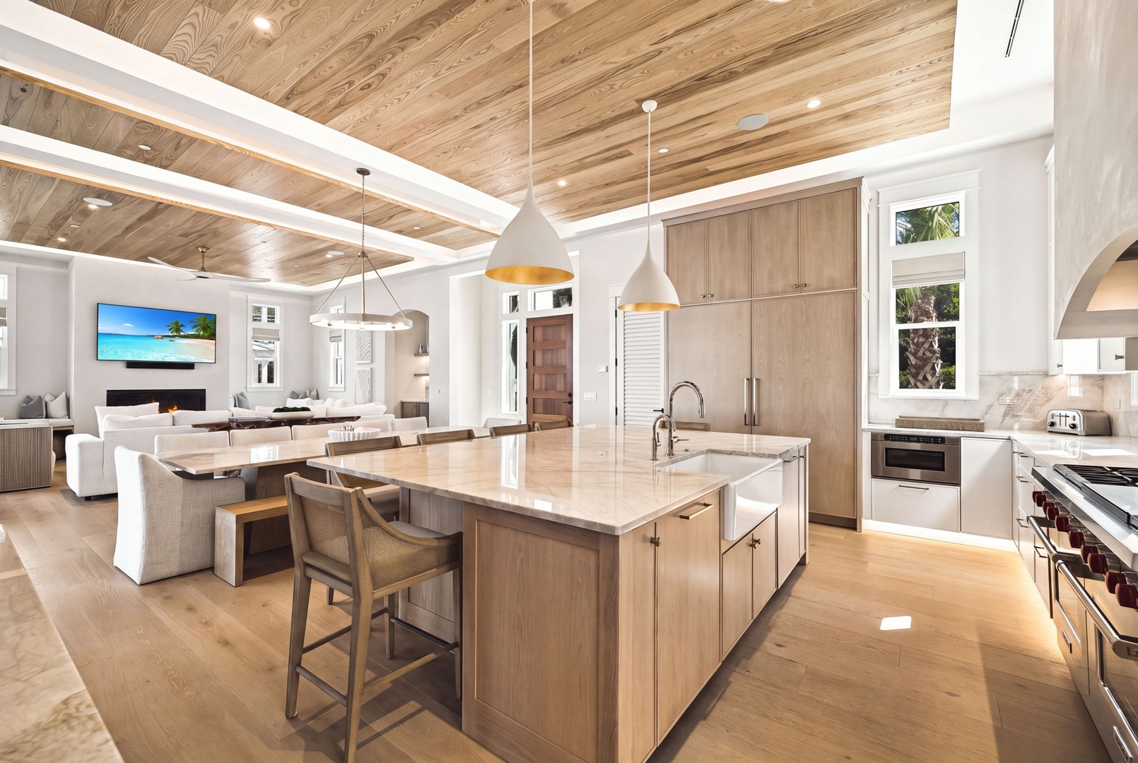 Open-concept kitchen and living area with soaring wood ceilings, elegant pendant lighting, and spacious island—perfect for cooking, connecting, and relaxing.