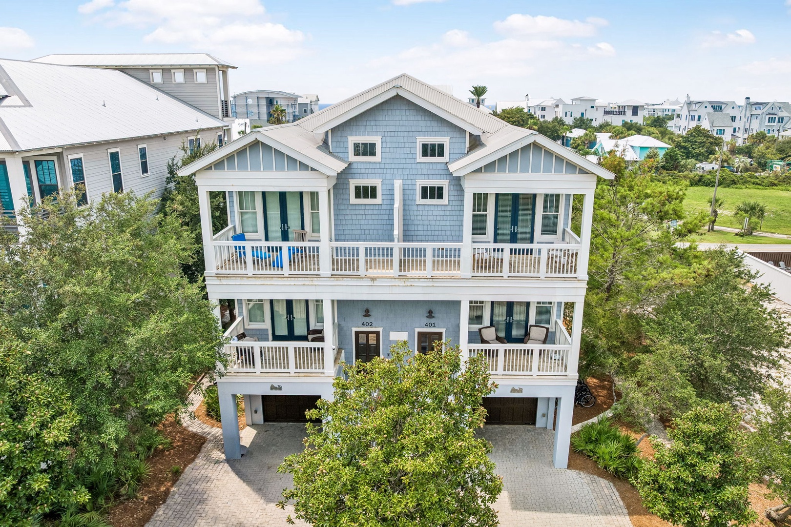 Charming coastal duplex with spacious balconies, nestled among lush greenery in a peaceful beachside neighborhood.