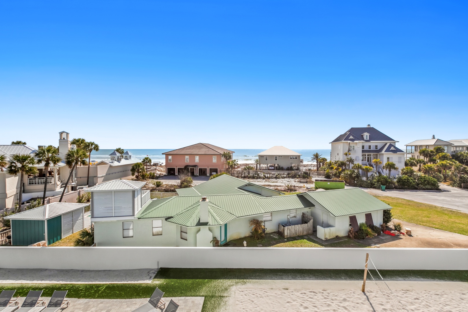 Aerial view of the property and surrounding beachfront neighborhood with ocean beyond.