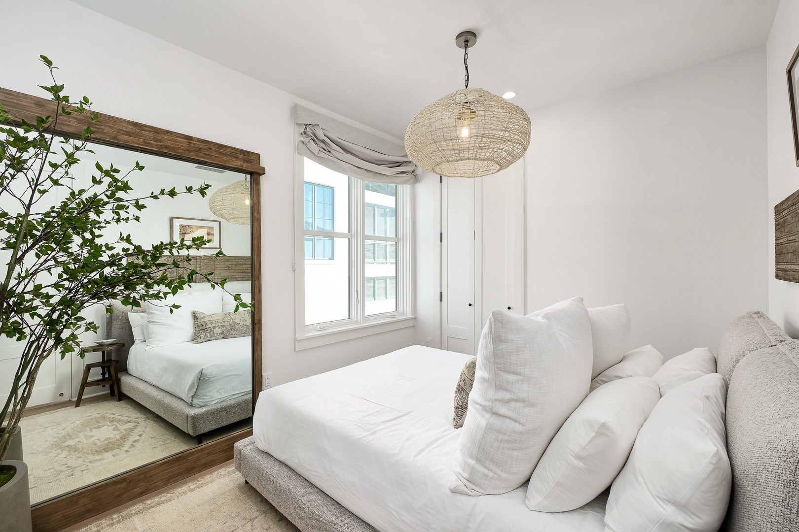 Sink into plush white bedding under a stunning woven pendant light. Natural light pours through windows while warm wood accents create your peaceful retreat.