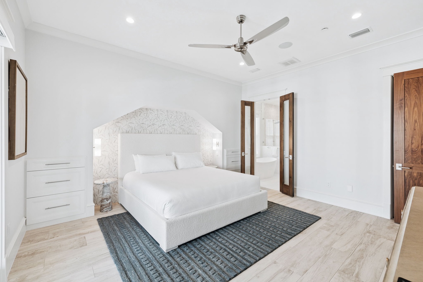 Drift into serene sleep on crisp white linens beneath decorative molding and gentle ceiling fan breezes in this tranquil master retreat.