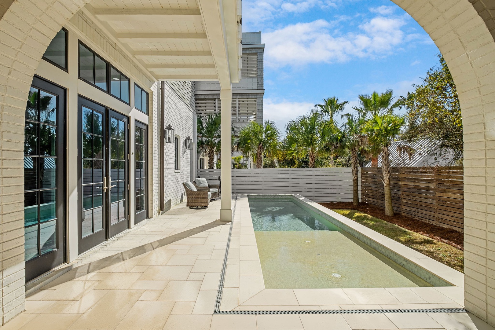 Your private oasis awaits with a sparkling pool, comfortable patio seating, and tropical palms creating the perfect backdrop for relaxation.