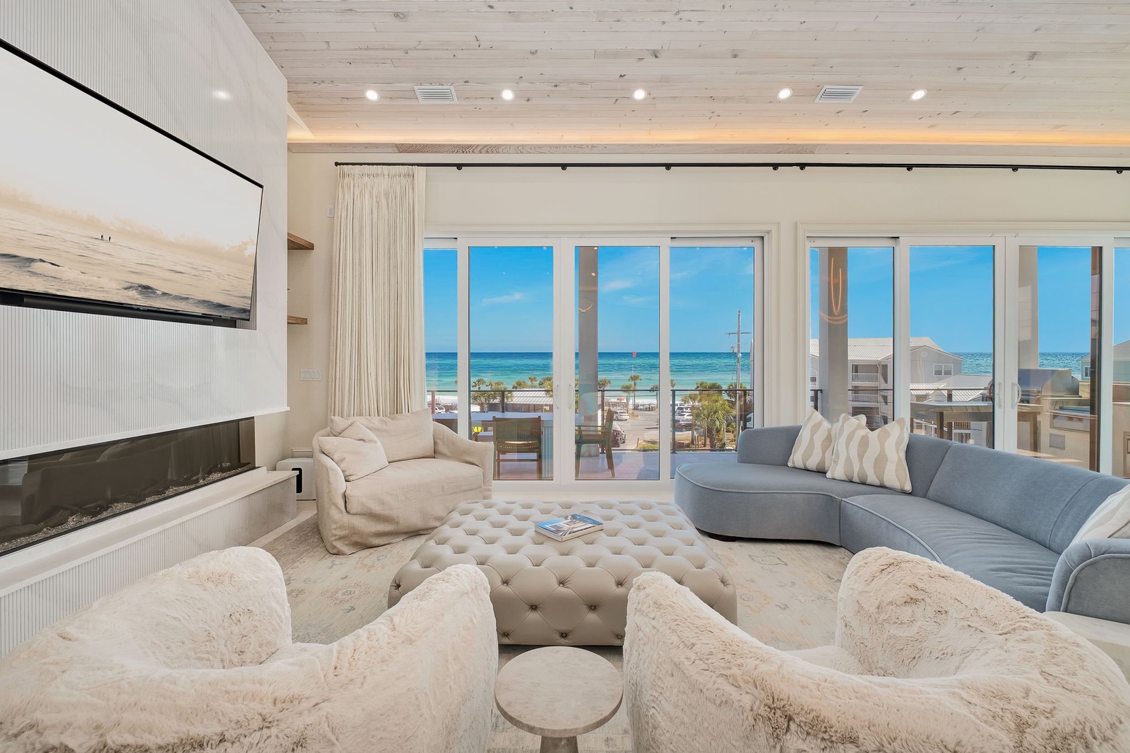 Sink into plush seating while the ocean unfolds through floor-to-ceiling windows. Cozy textures, warm wood ceilings, and a fireplace create your perfect beach retreat.