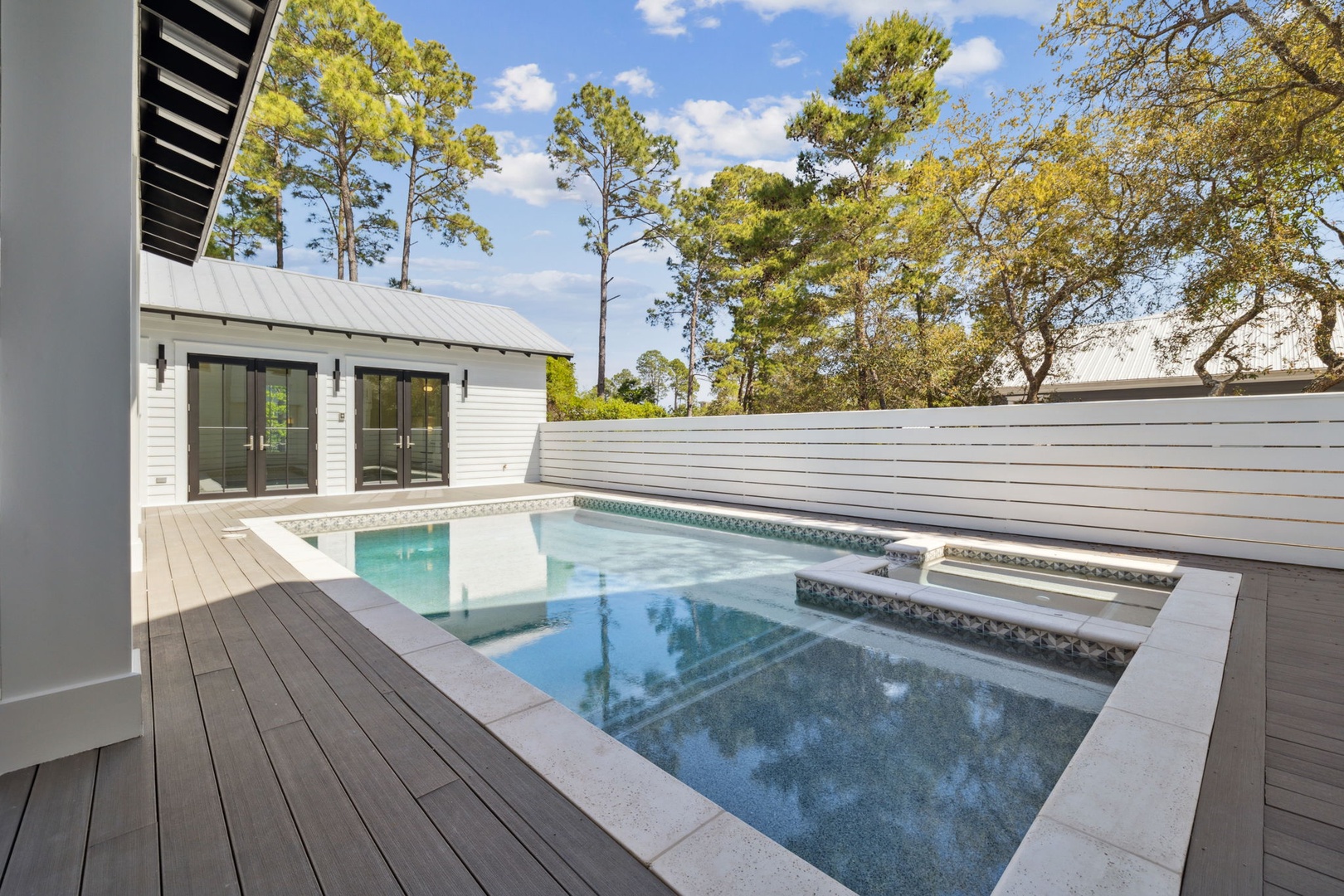 Your private pool oasis awaits, surrounded by elegant decking and towering pines for ultimate relaxation.