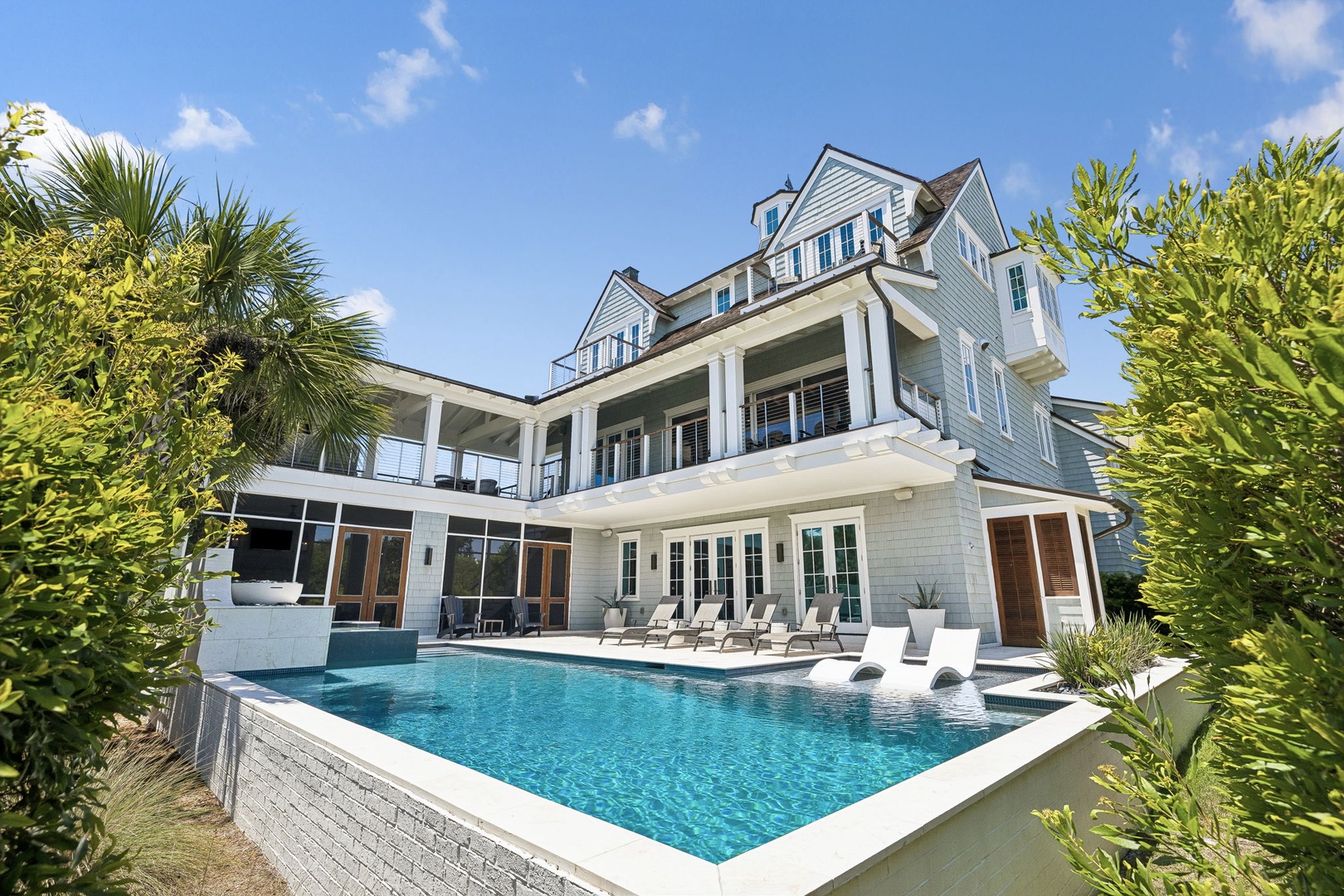 A stunning coastal estate featuring a sparkling pool, spacious terraces, and lush tropical landscaping under bright blue skies—perfect for relaxing getaways.