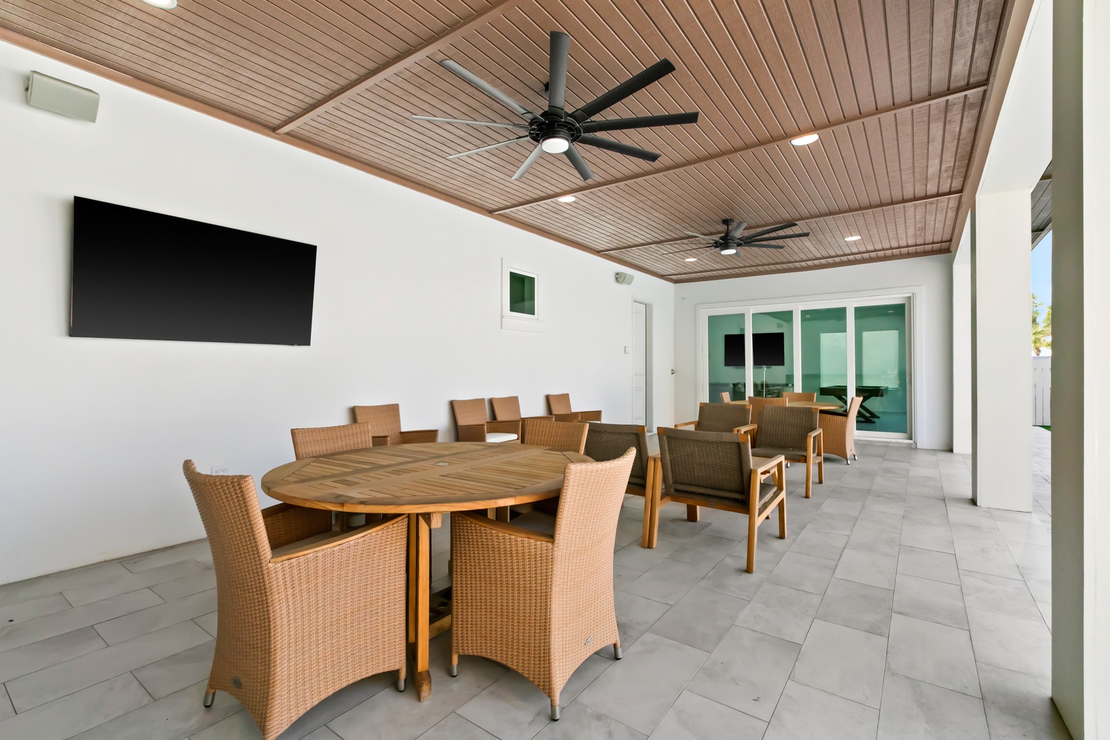 Gather around the large dining table on this covered patio, where ceiling fans keep you cool and a flat-screen TV sets the scene for memorable meals and long conversations with friends and family.