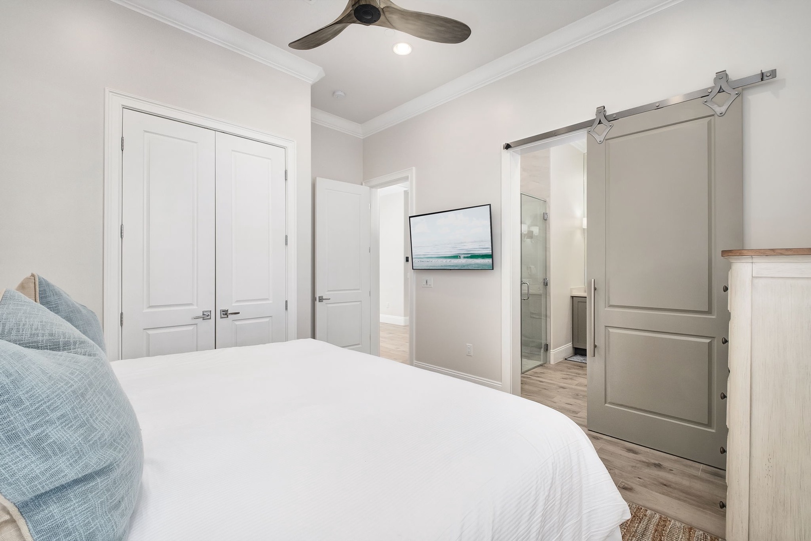 Your coastal bedroom retreat features plush linens and a spacious en-suite with elegant sliding barn doors for privacy.
