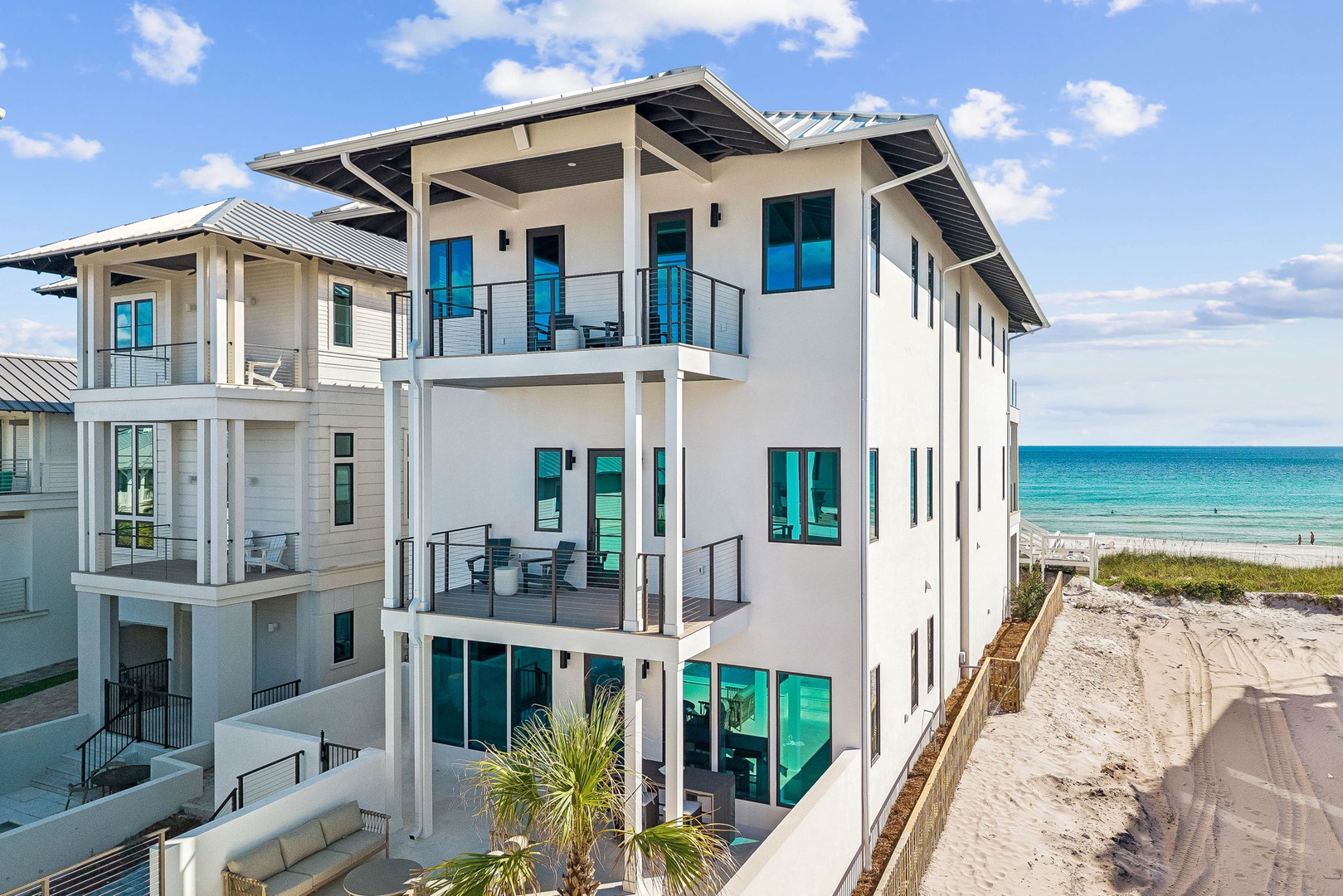 This beachfront property features modern architecture with spacious balconies, positioned directly along pristine sandy shores with turquoise waters. The multi-level building offers direct beach access and contemporary coastal design.