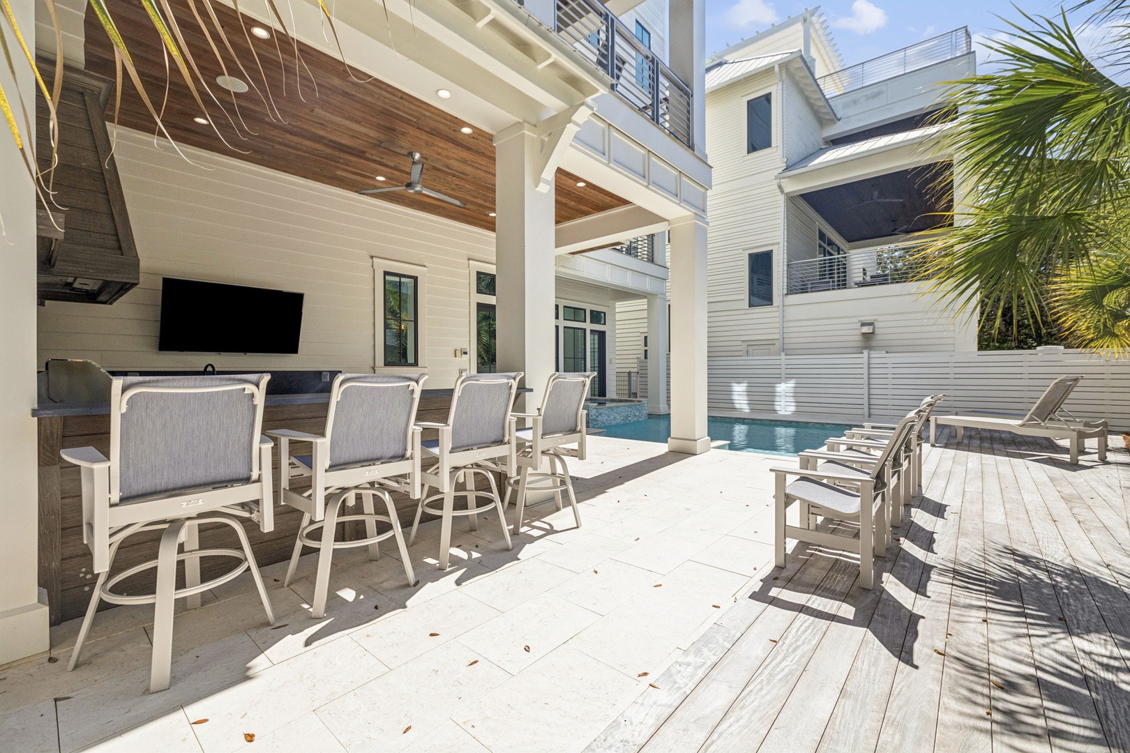 Your perfect poolside retreat features bar seating and loungers overlooking the sparkling water, with modern outdoor entertainment ready for relaxation.