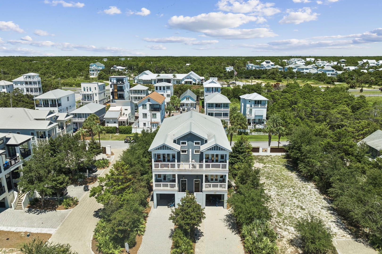 Aerial view of a coastal neighborhood with beach-style homes nestled among lush greenery, offering a tranquil setting near the shore.
