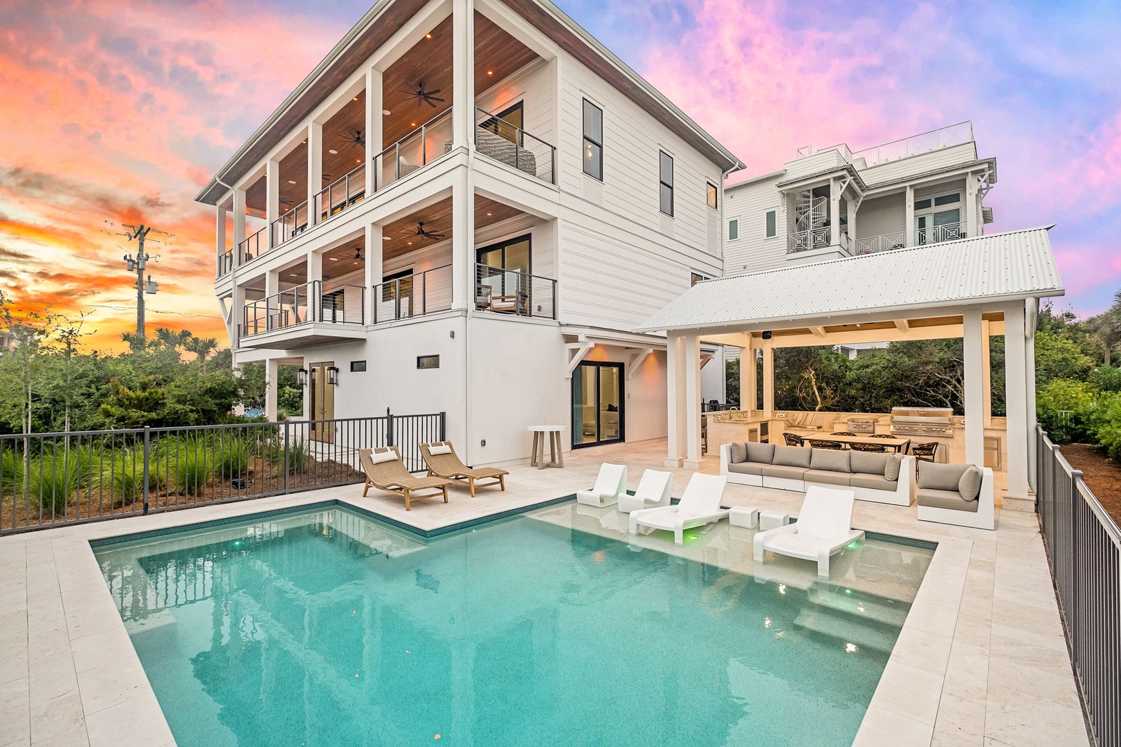 Modern coastal retreat with private pool, covered lounging area, and stunning sunset views. The spacious outdoor entertaining space features a built-in seating area perfect for gathering with friends and family.