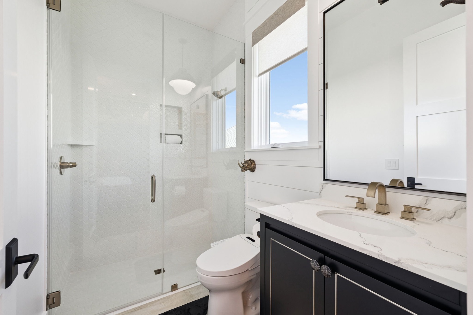 Refresh in your private spa-style bathroom with marble countertops, rainfall shower, and natural light streaming through the window.