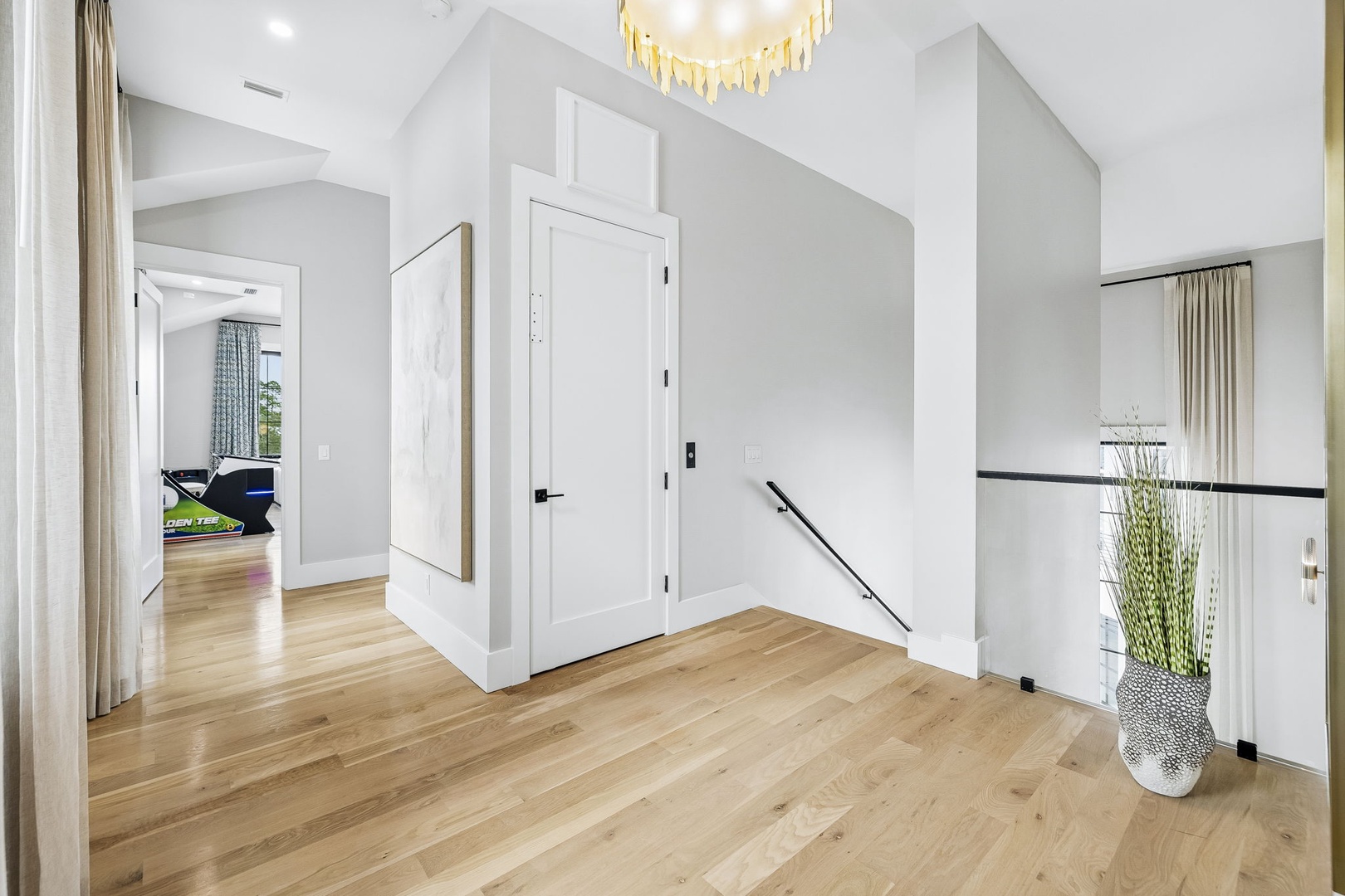 Step into a bright, modern hallway with warm wood floors and elegant lighting overhead. Clean lines and airy openness invite you to explore your retreat.