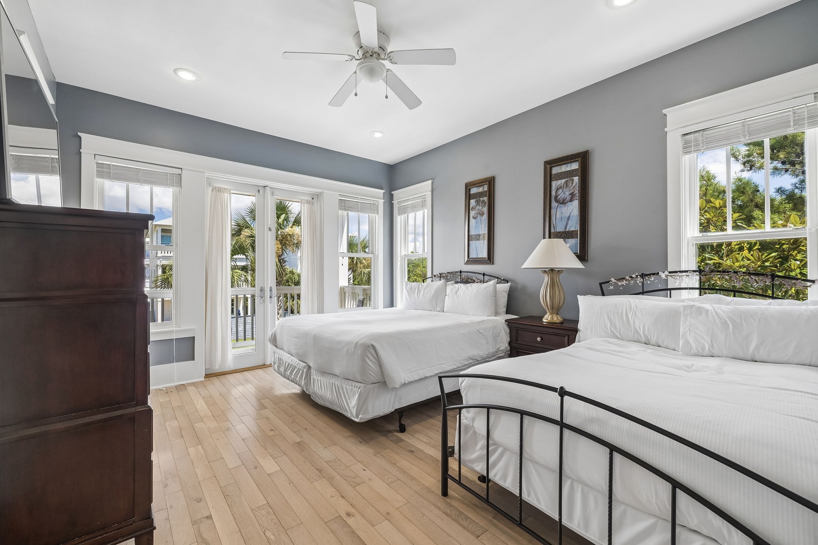 Drift off in this bright coastal bedroom, where sunlight and gentle breezes flow through the balcony doors, and two plush beds promise restful nights after your beach adventures.