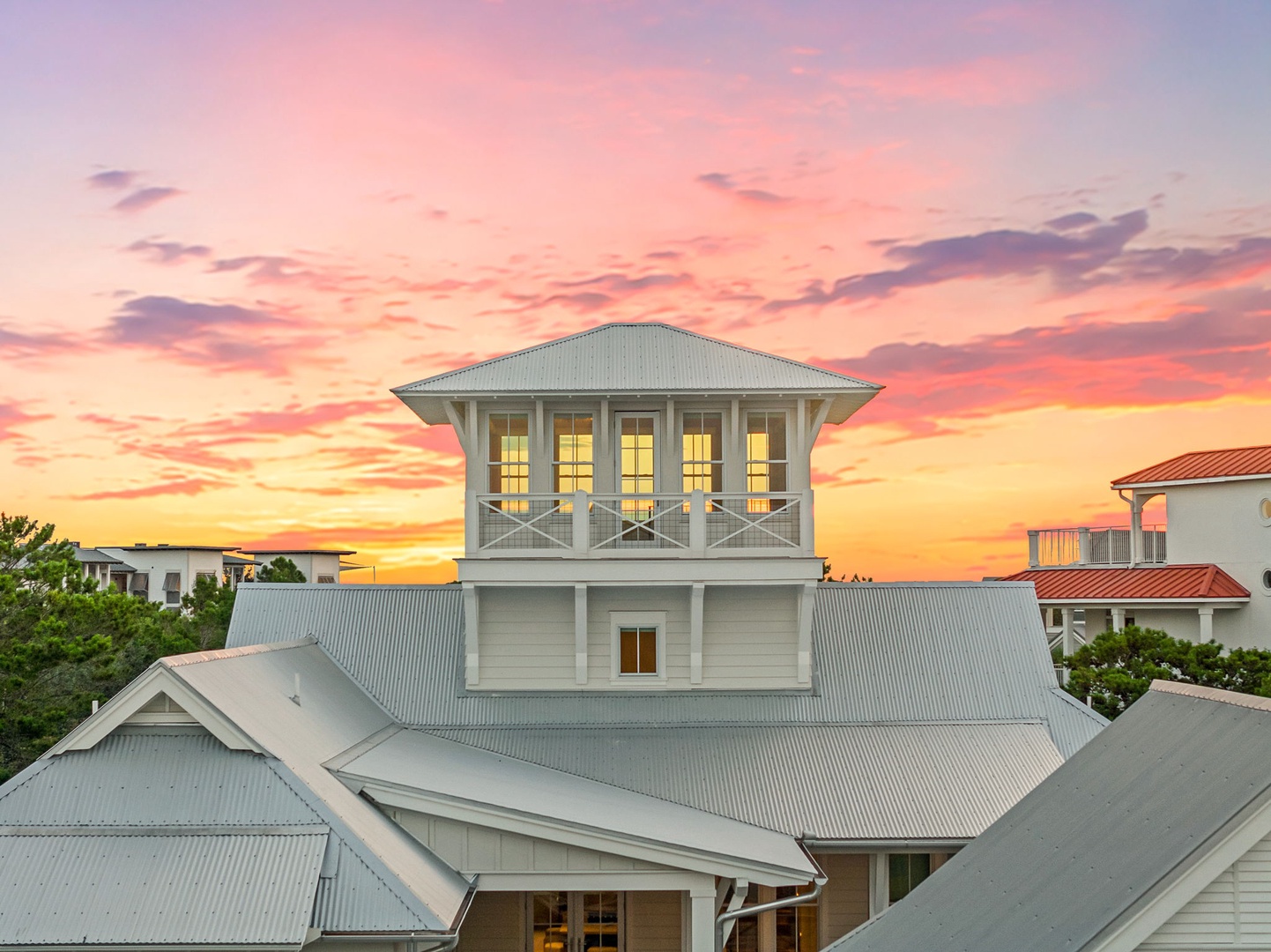 A stunning coastal property framed by a vivid sunset, offering a peaceful neighborhood setting just moments from the shore.