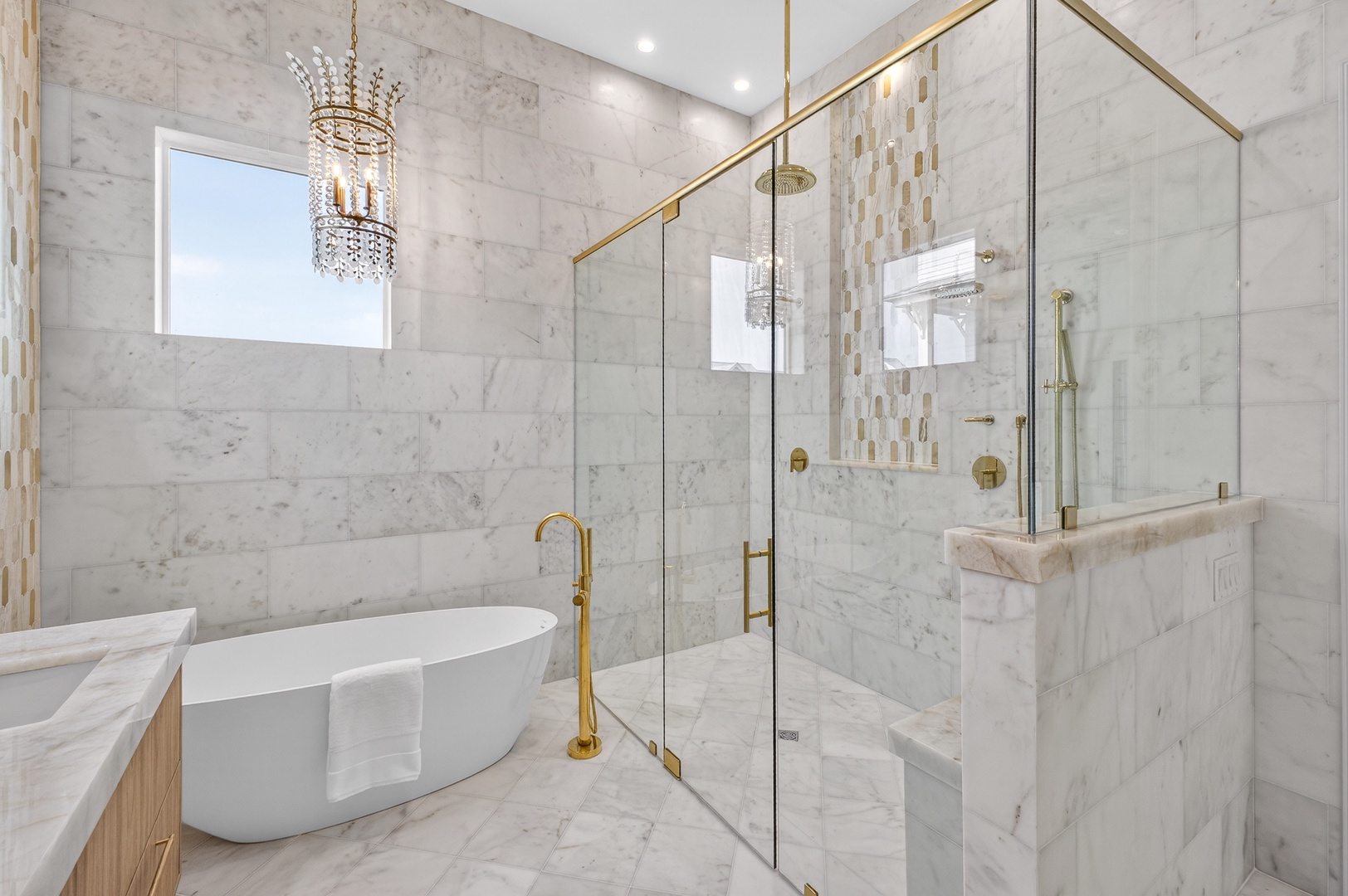 Indulge in your own marble sanctuary with a luxurious soaking tub and stunning glass-enclosed shower featuring elegant gold fixtures.