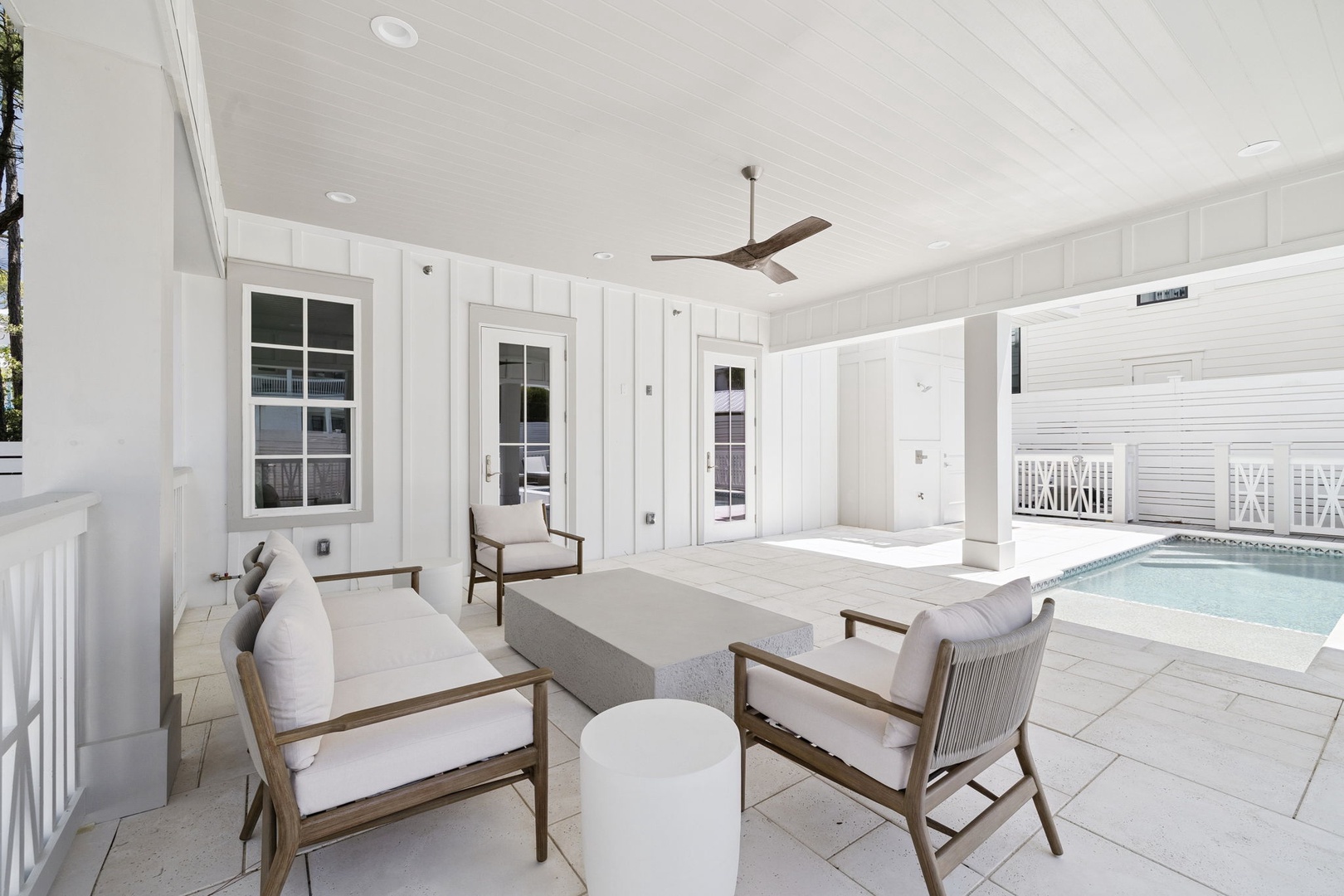 Relax in your elegant covered patio with comfortable seating overlooking the sparkling pool, perfect for morning coffee or evening unwinding.