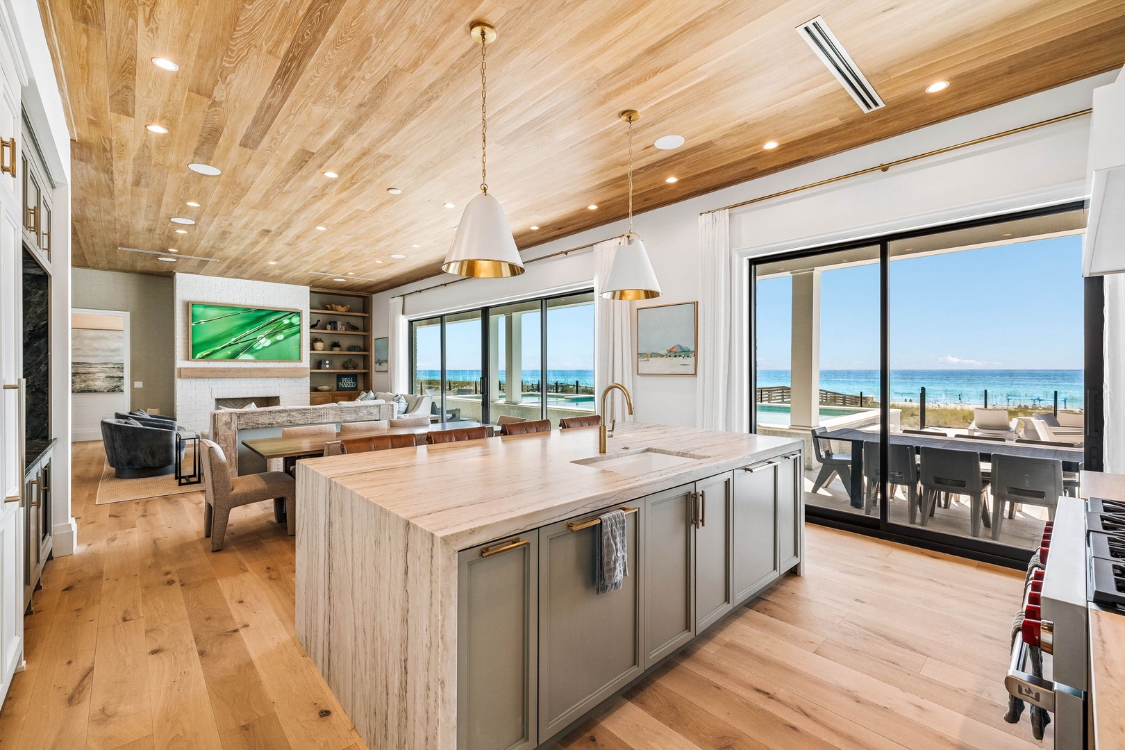 Open-concept living with natural wood tones and modern design. Floor-to-ceiling windows frame sweeping water views while the chef's kitchen island becomes the heart of gathering and memory-making.